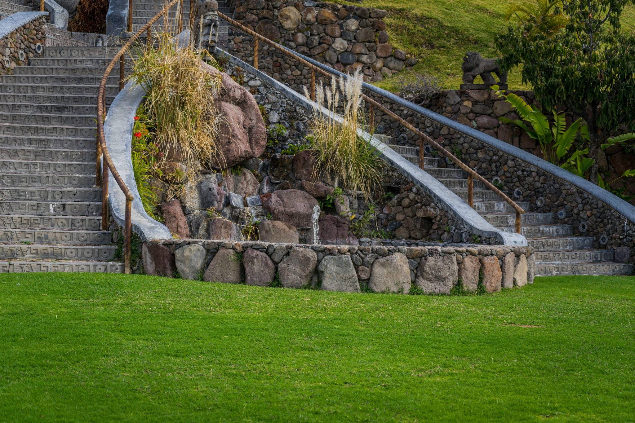 A beautiful stone staircase and lush green lawn create an exotic garden ambiance.