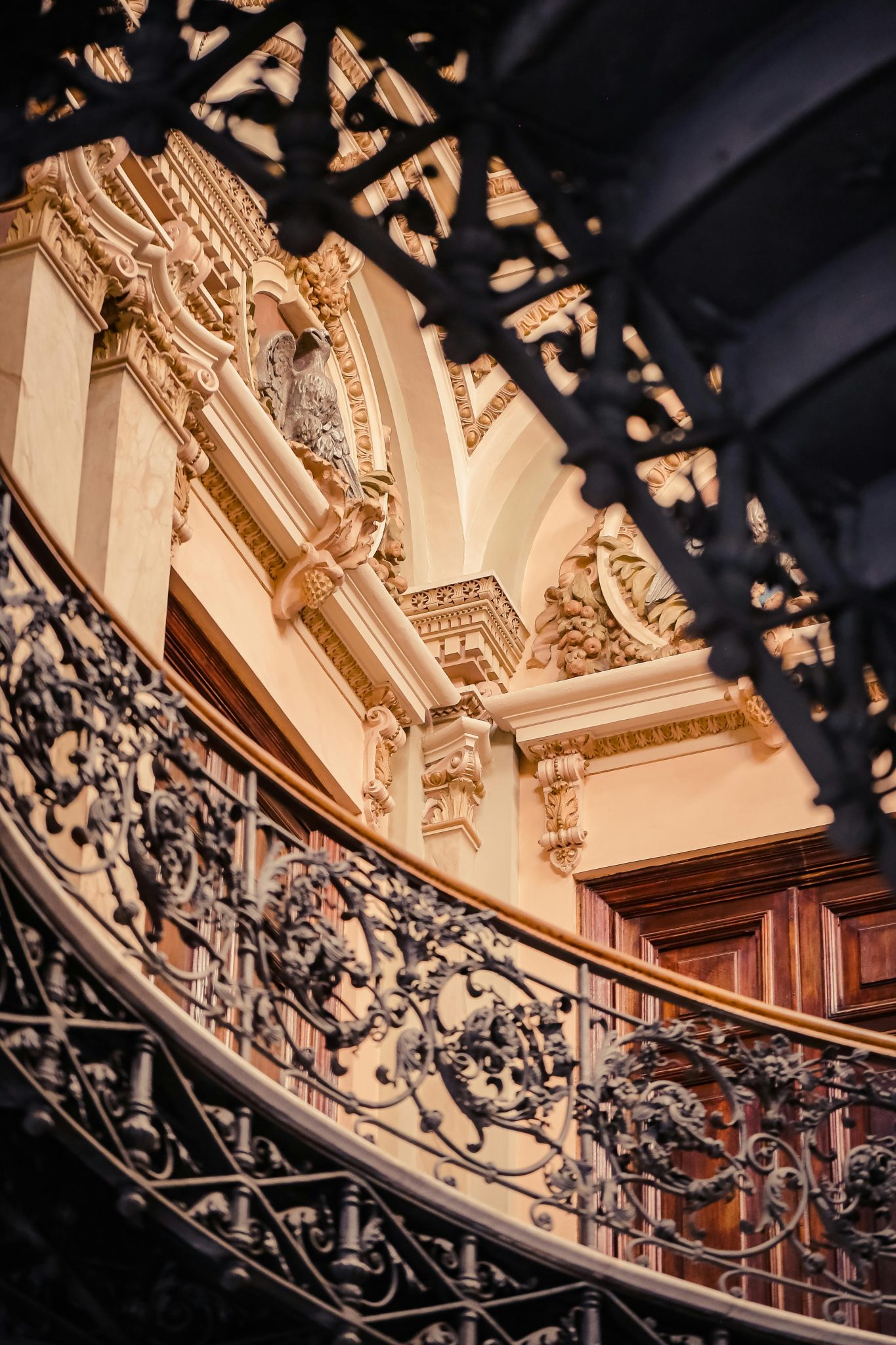 A beautifully detailed spiral staircase with elaborate wrought iron railings in a classic interior.