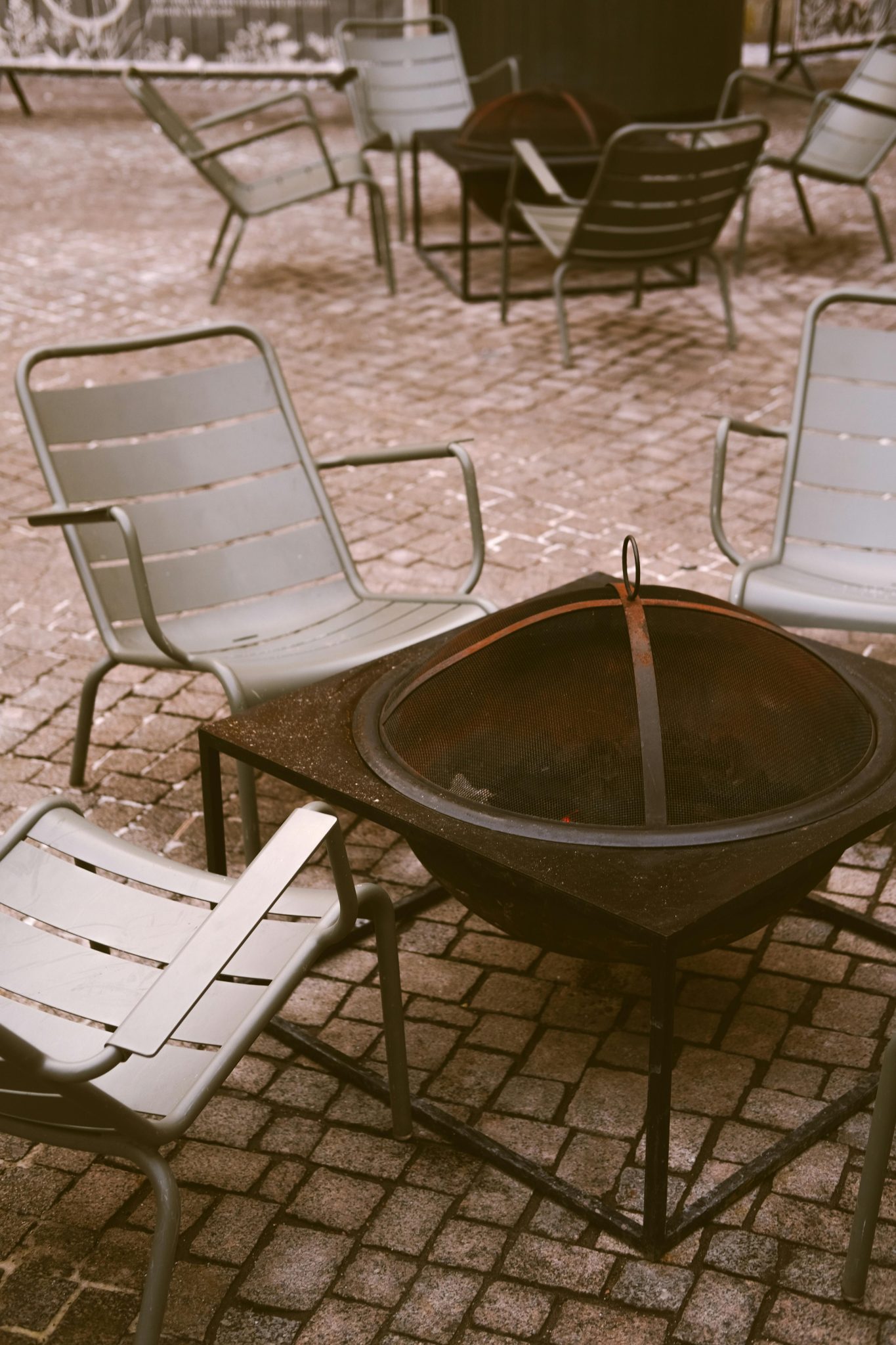 A charming outdoor patio scene featuring chairs and a central fire pit perfect for cozy gatherings.