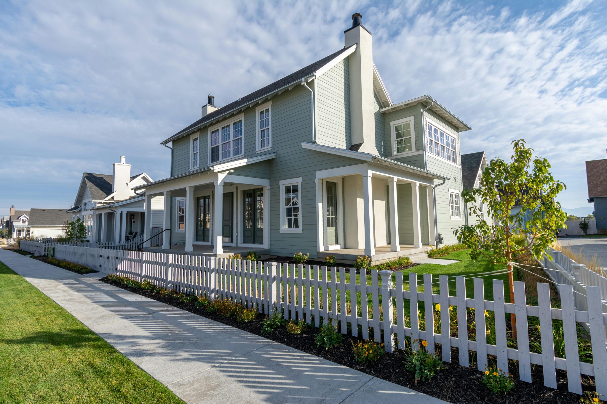 A charming suburban house with a white picket fence and clear skies, perfect for family living.