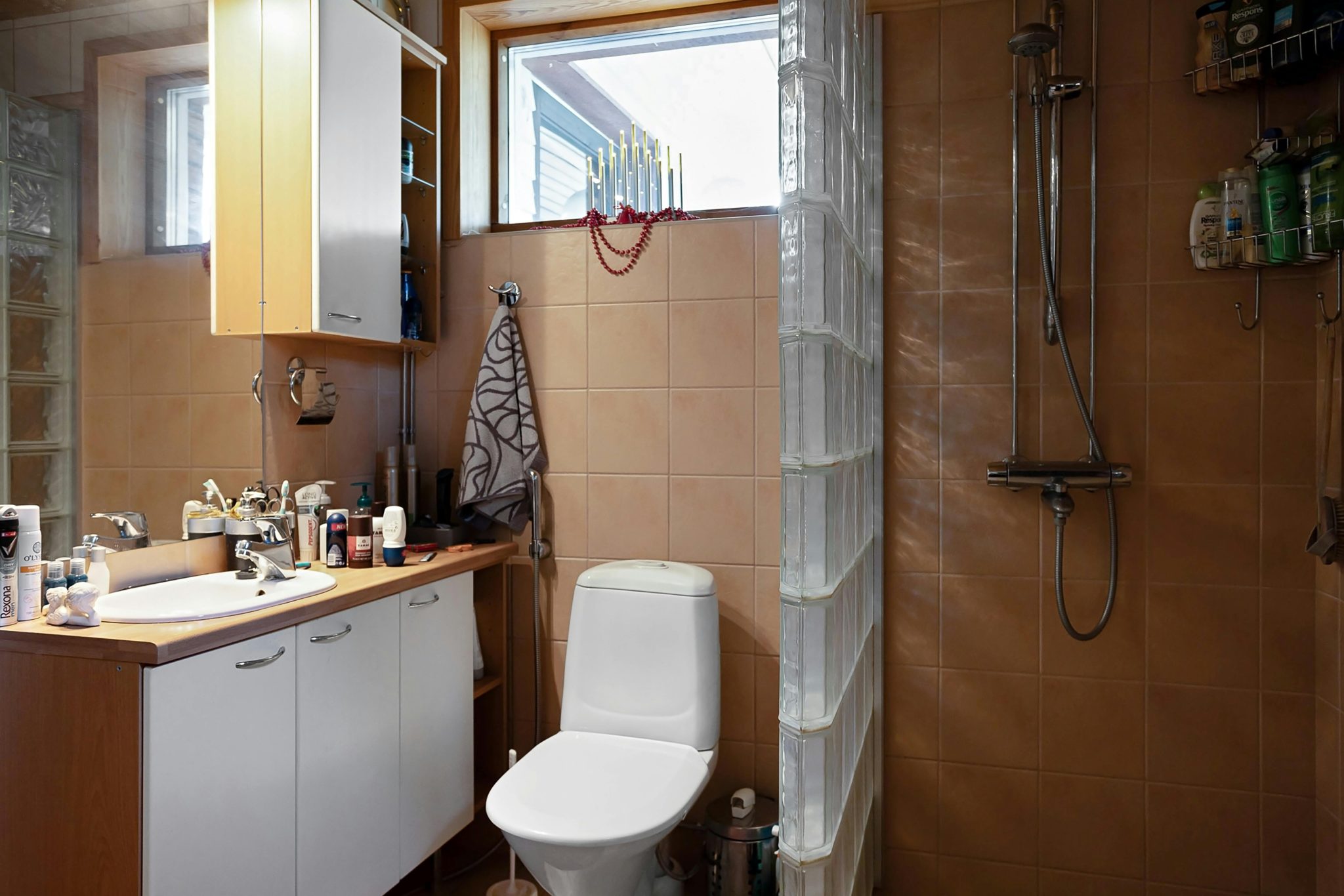 A contemporary bathroom featuring a shower, sink, and vanity with natural light from the window.
