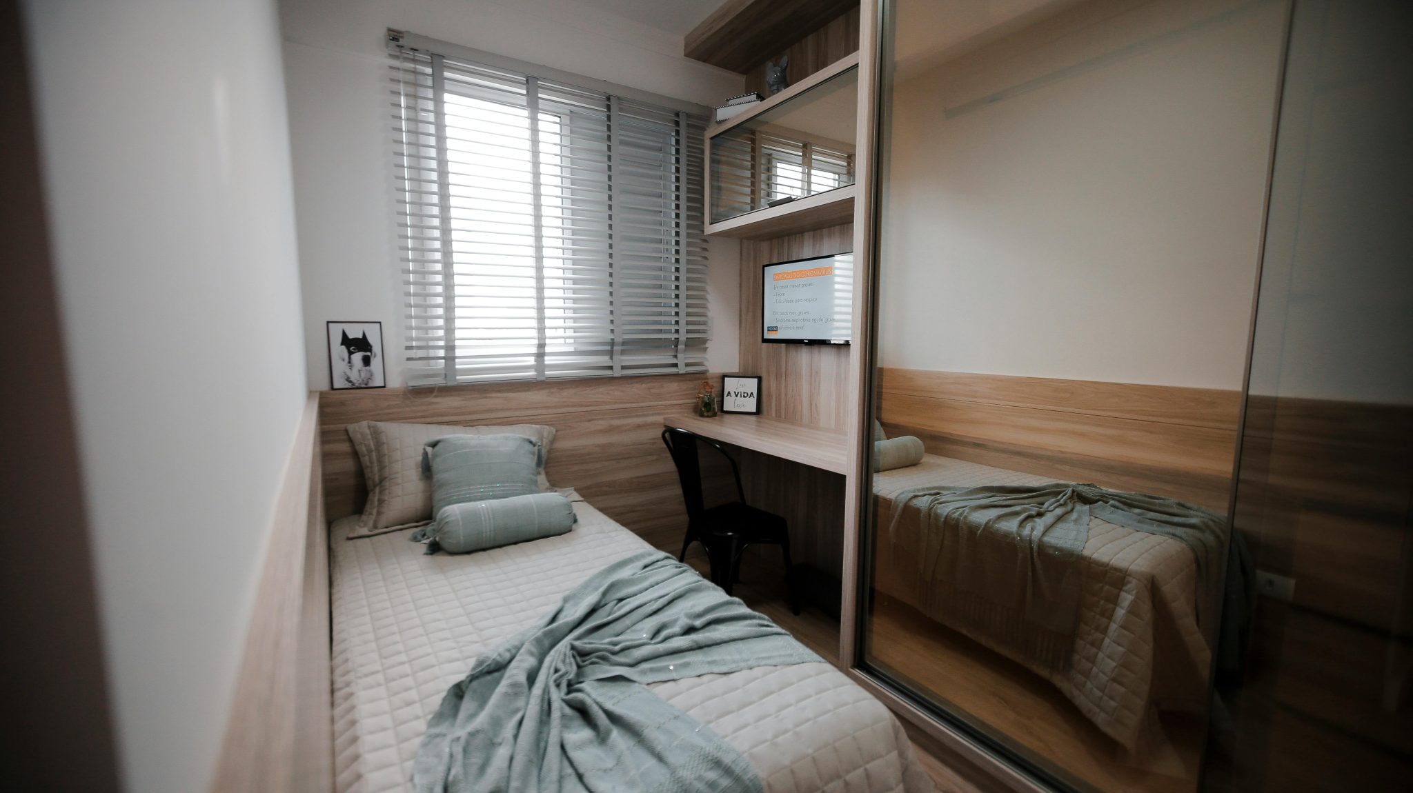 A cozy and minimalist bedroom interior featuring a single bed and a small workspace.