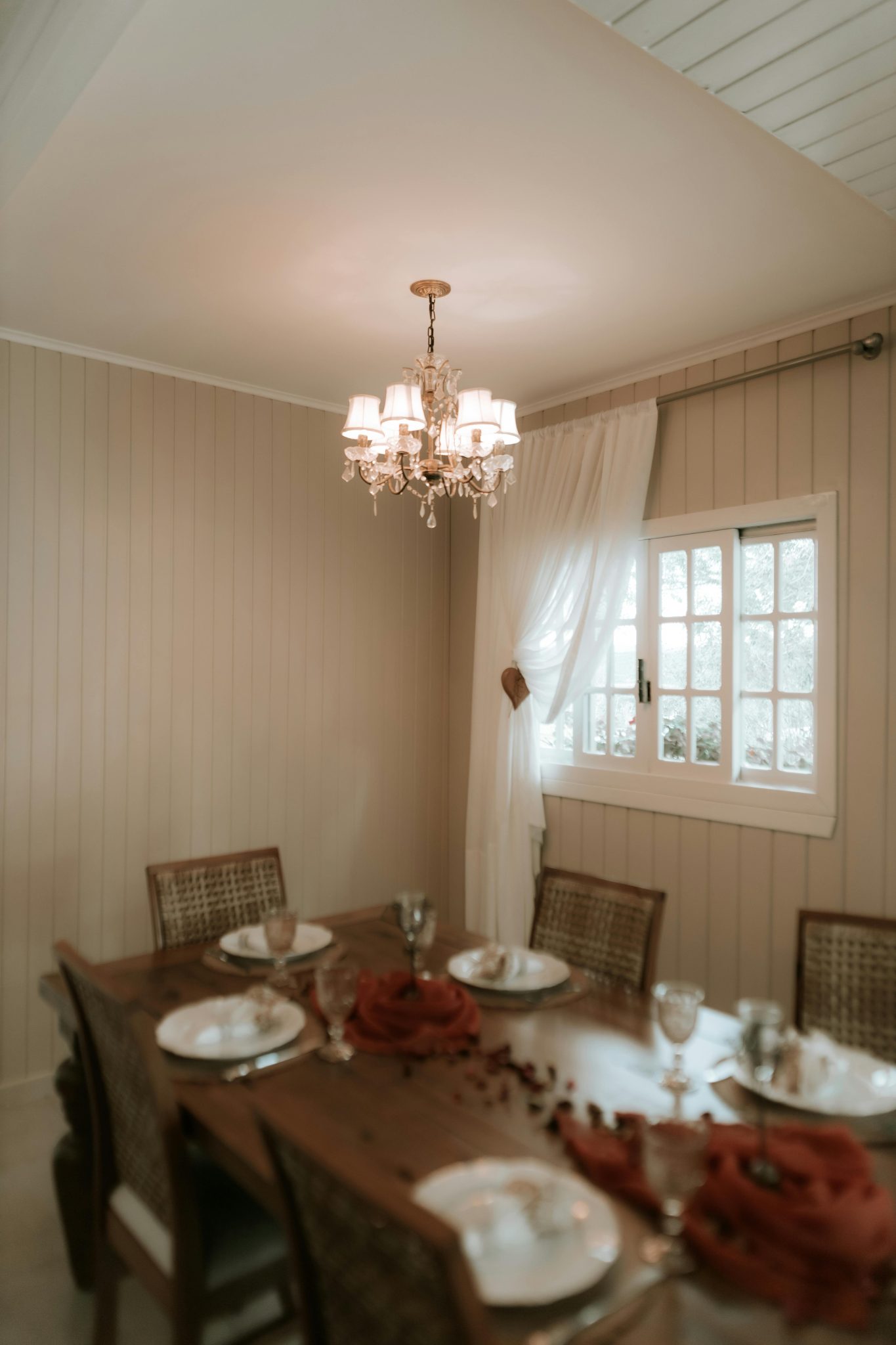 A cozy dining area with a classic chandelier and a wooden table set for dinner.