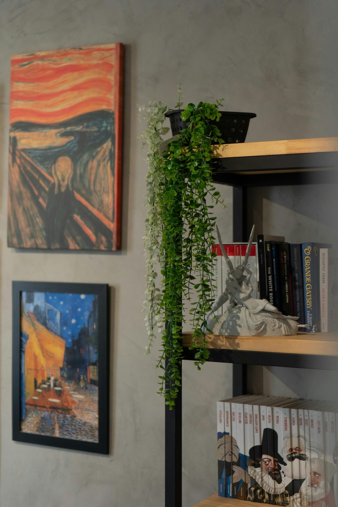 A cozy interior with art, a bookshelf, books, and a hanging plant, perfect for home decor inspiration.