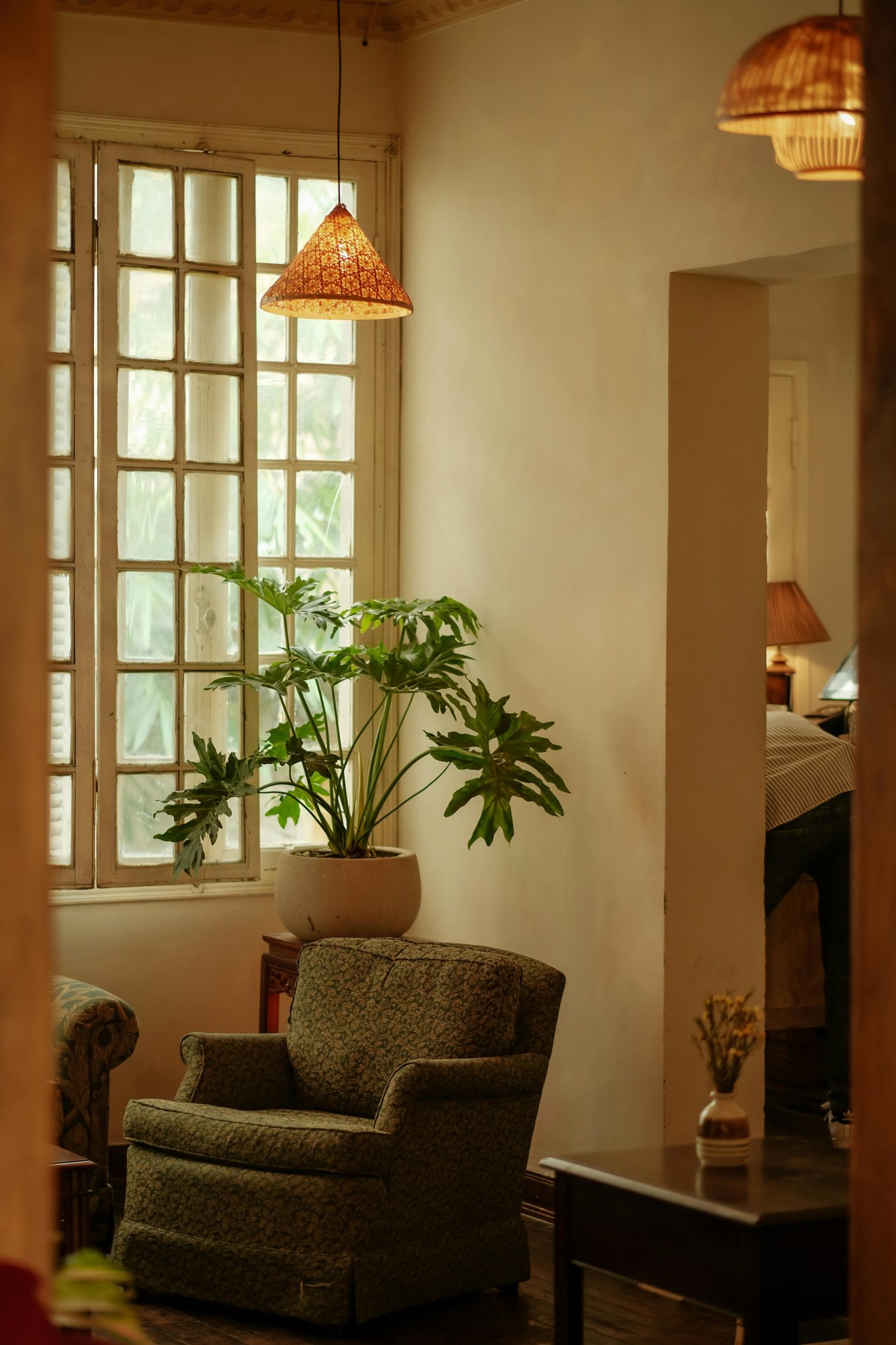 A cozy living room setup featuring a comfortable armchair and lush houseplant near a large window.