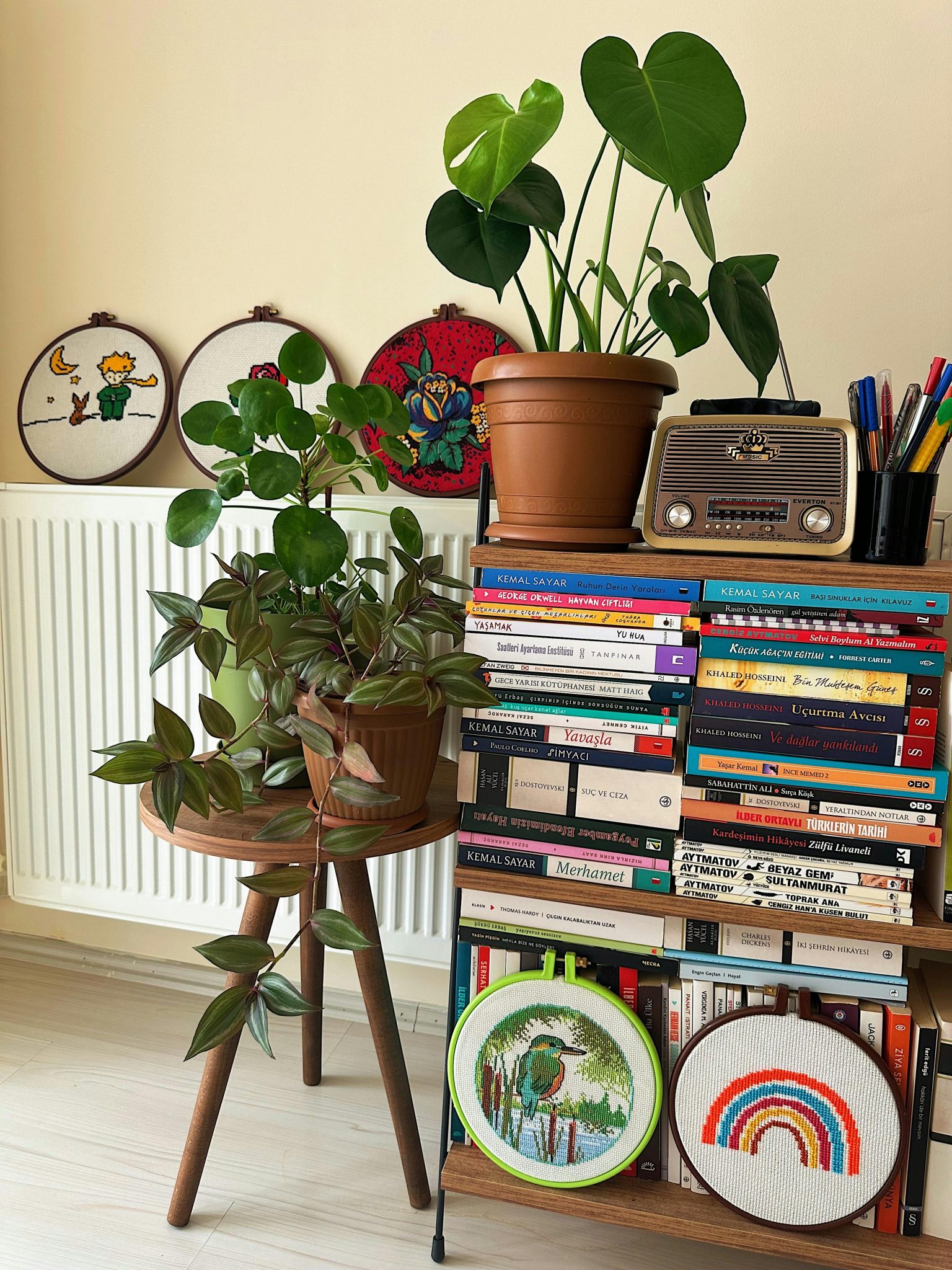 A cozy living space featuring lush plants, a bookshelf with diverse books, and vintage decor.