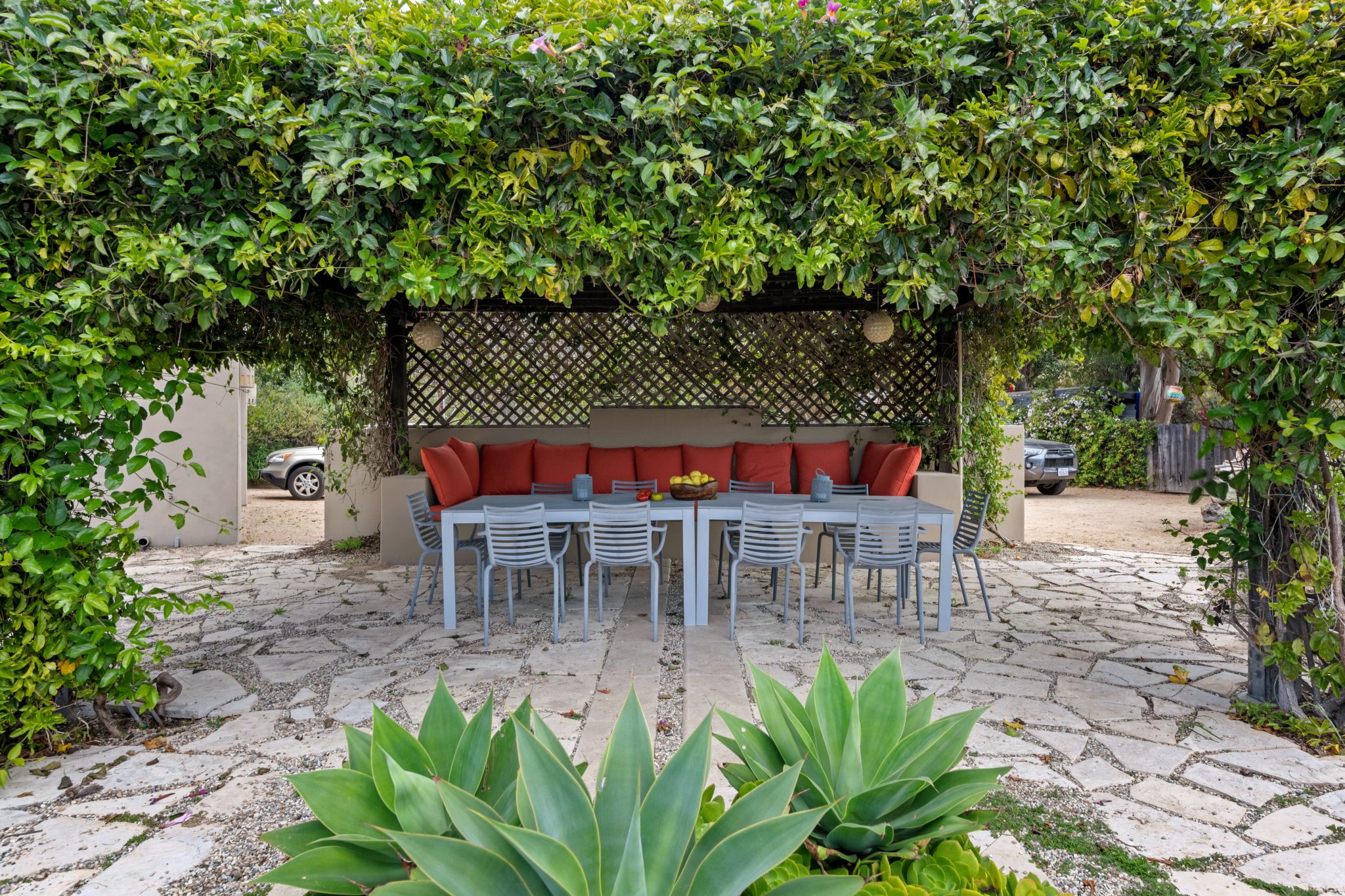 A cozy outdoor patio with furniture surrounded by vibrant greenery and vines.