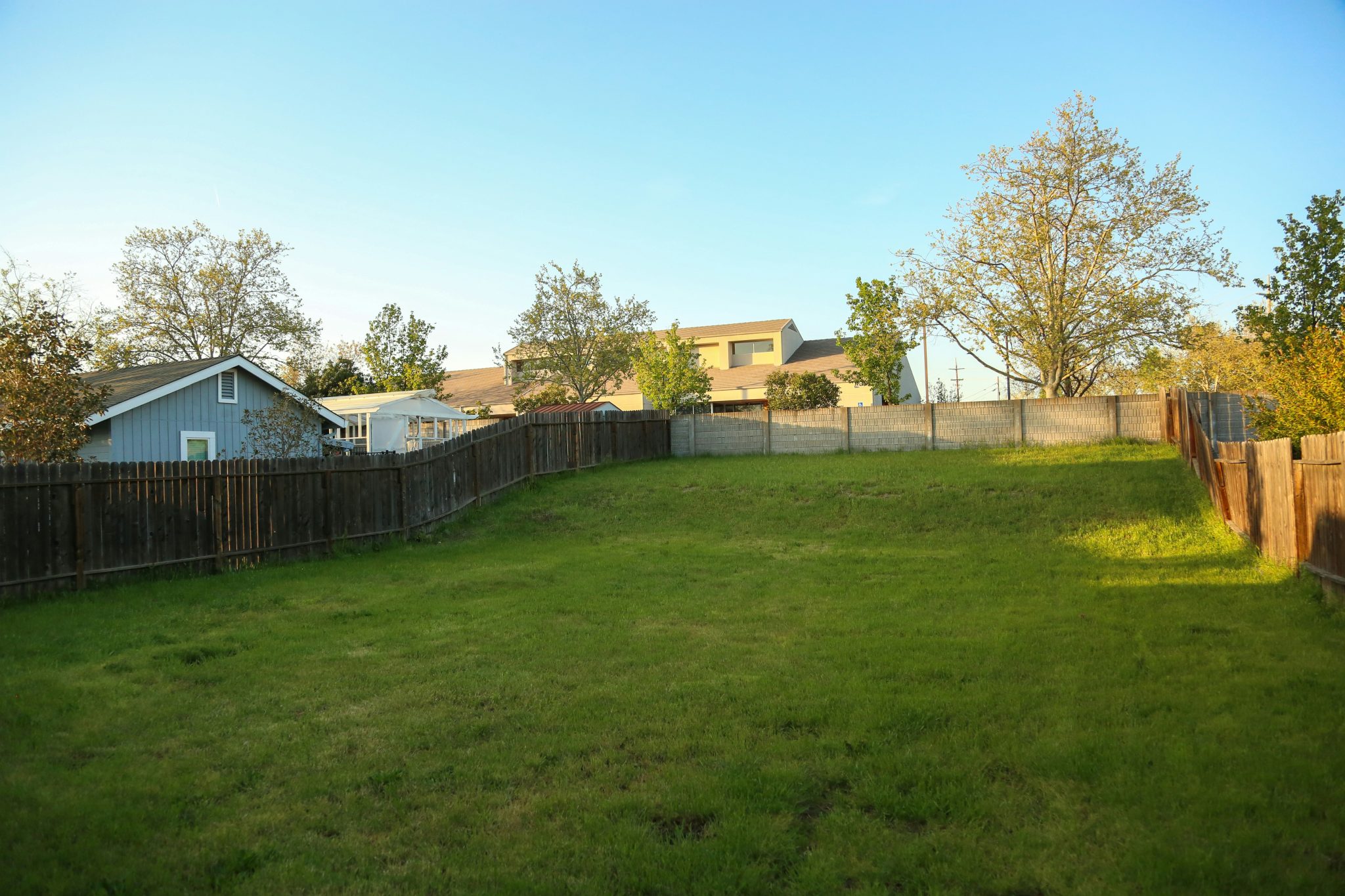 a grassy yard with a fence and a house in the background