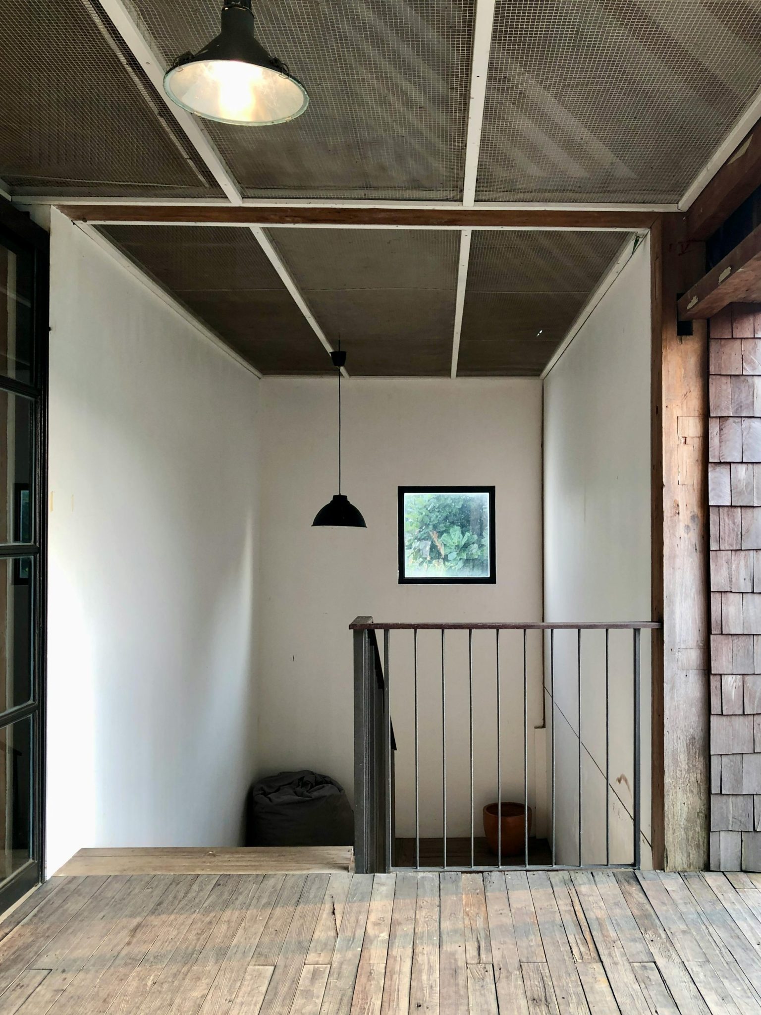 A minimalist interior design featuring a wooden floored staircase with a metal railing and pendant light.