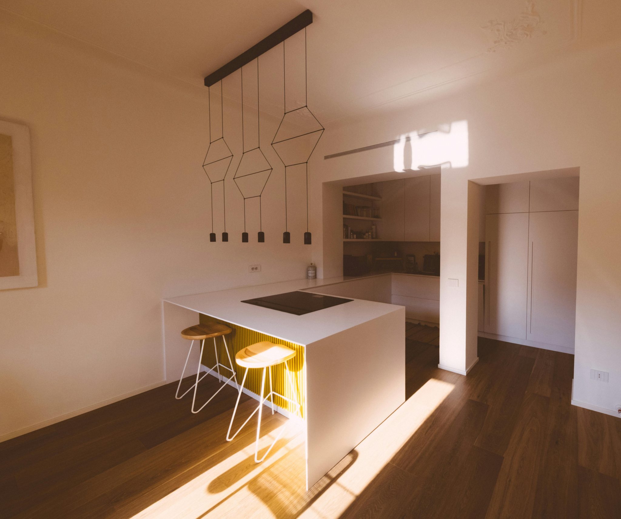 A minimalist kitchen interior with sleek lighting and wooden flooring.