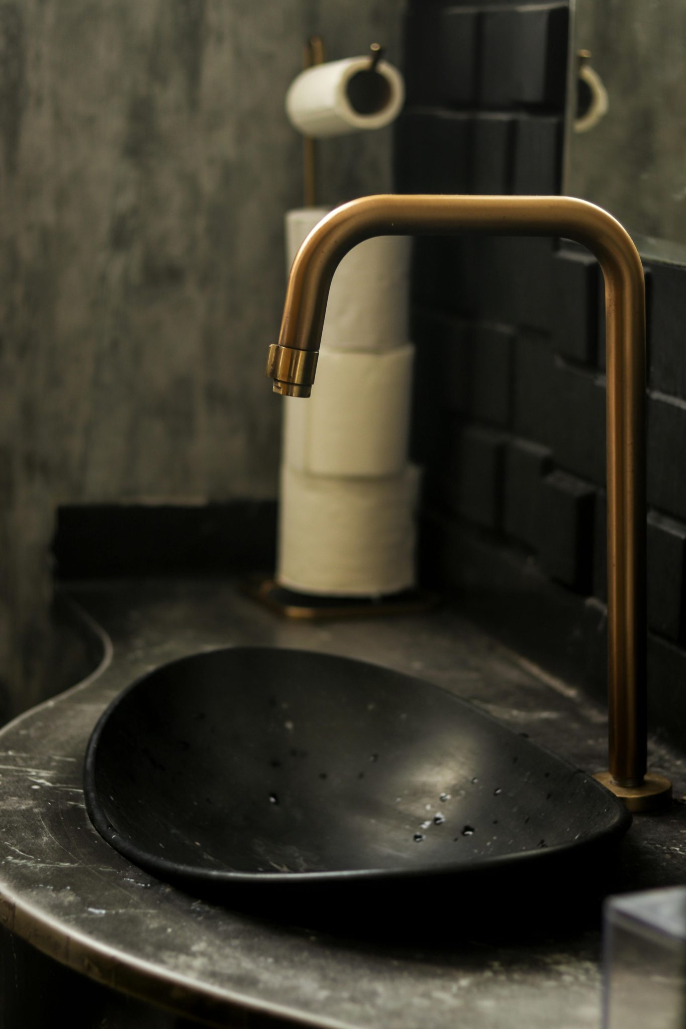 A modern bathroom sink with a sleek black basin and brass faucet, complemented by a stylish interior design.