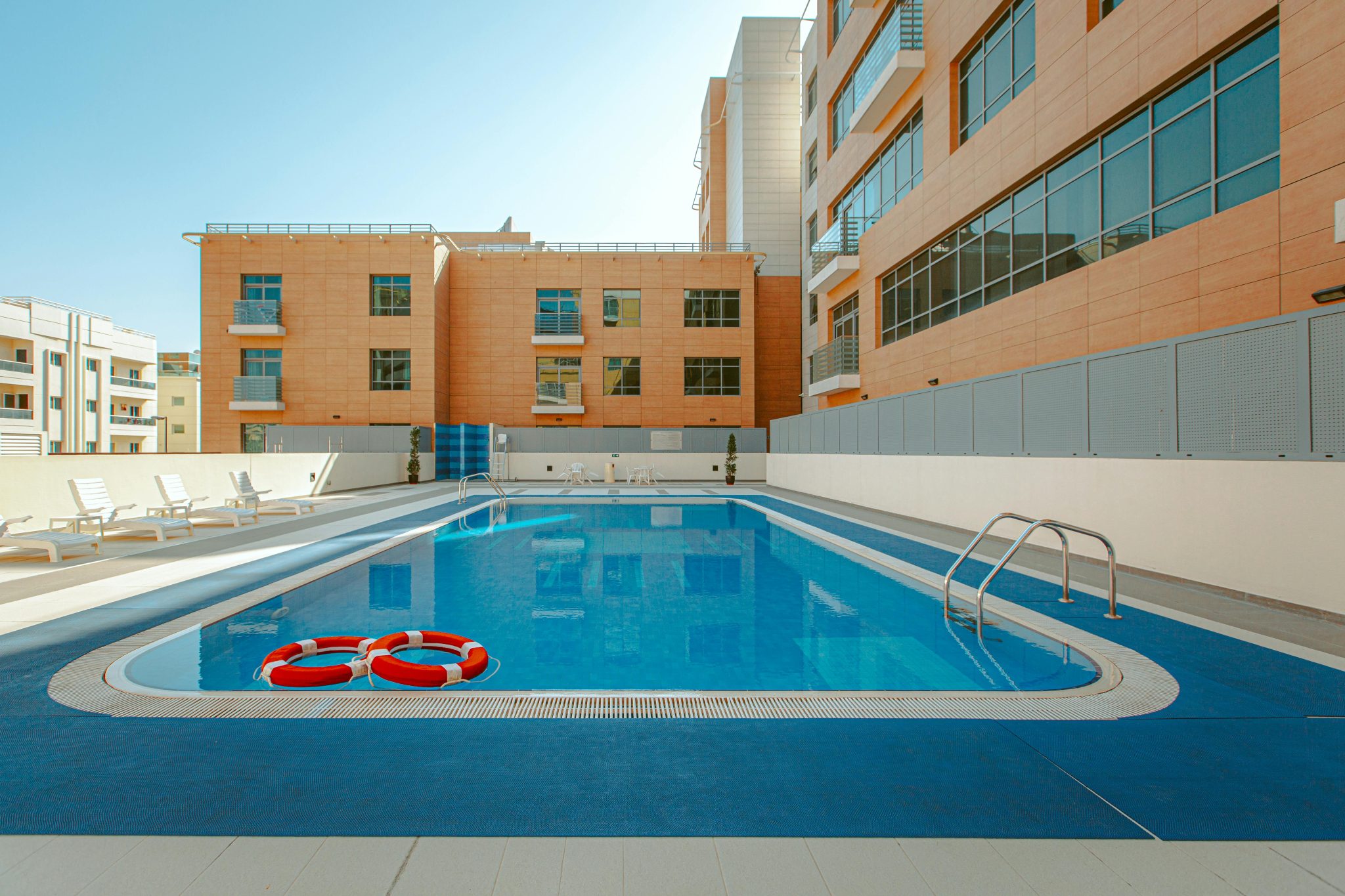 A rooftop swimming pool with clear blue water in a modern residential building.