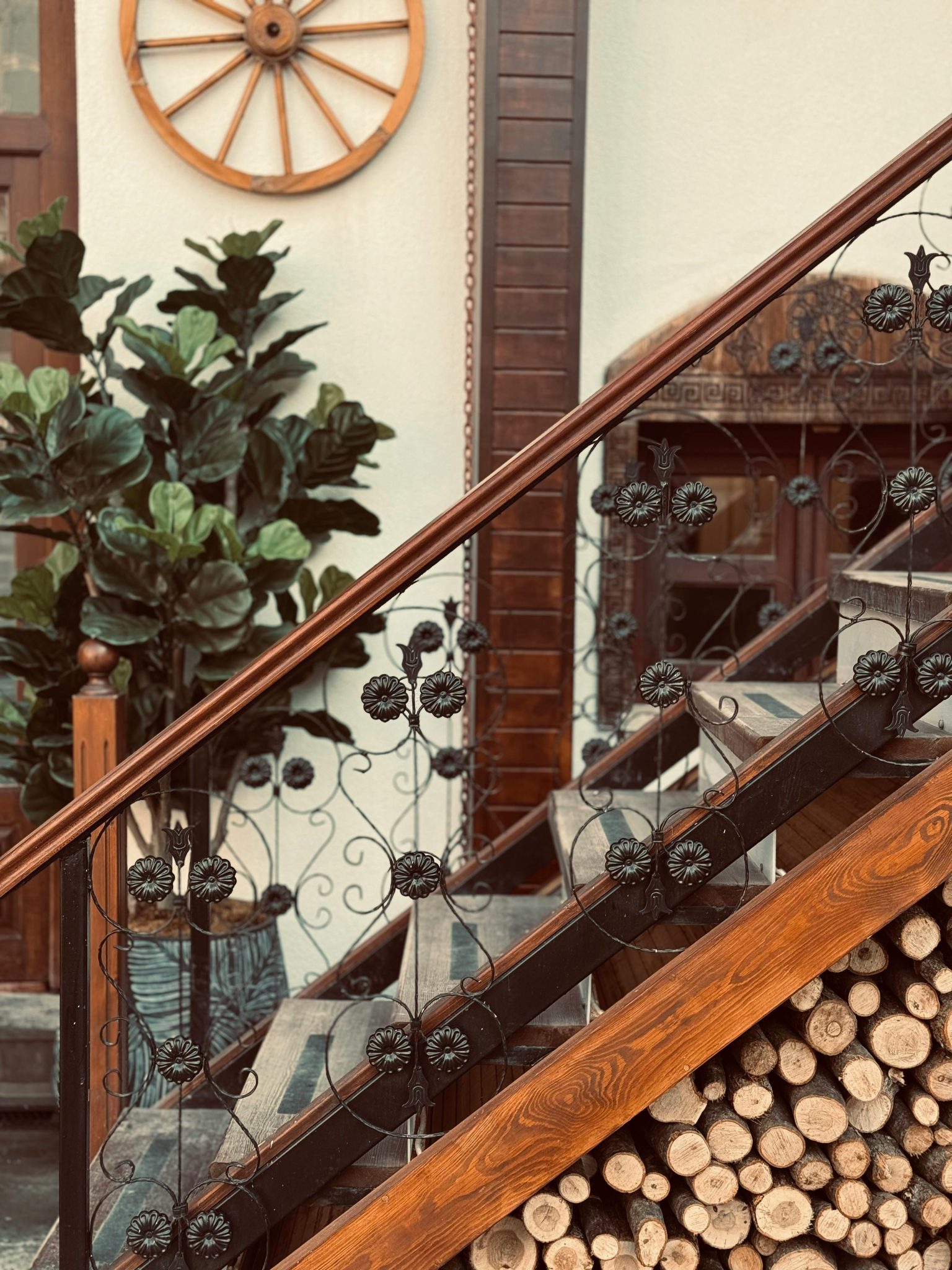 A rustic indoor staircase with decorative iron railing and wooden accents, featuring plant decor.