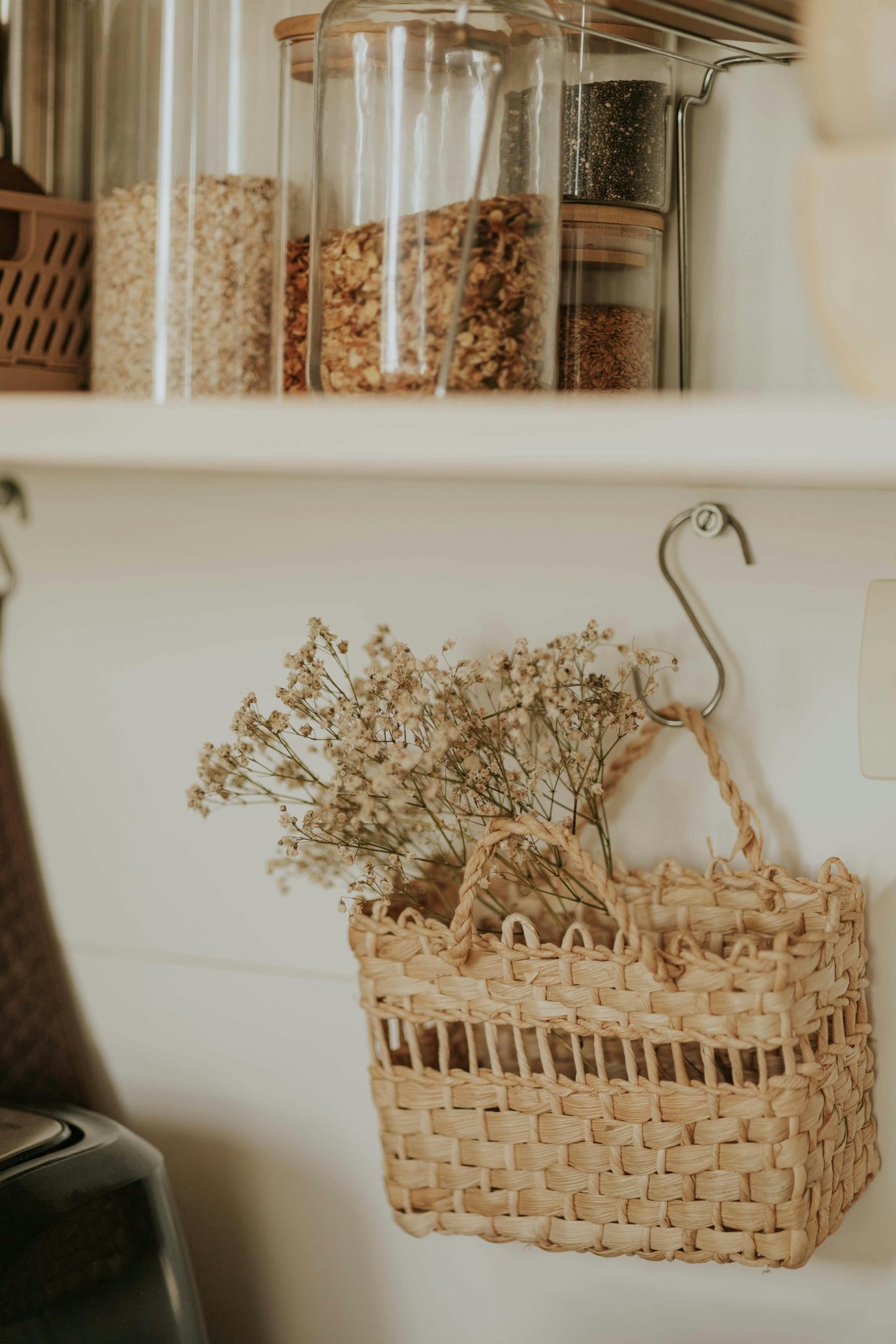 A rustic kitchen shelf with glass jars and wicker basket decor, evoking a cozy and warm ambiance.