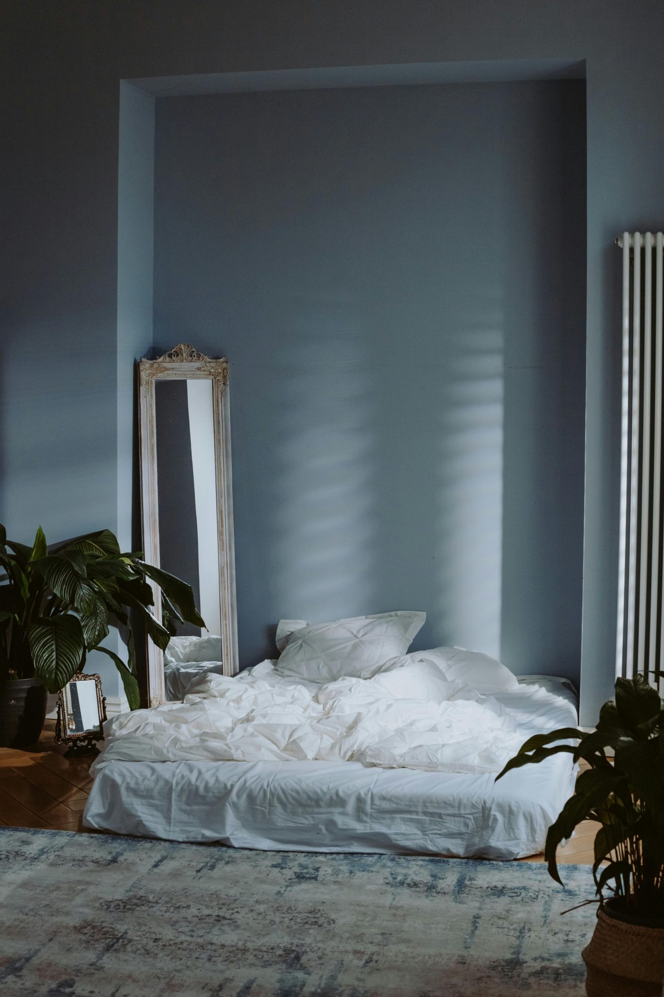 A serene and minimal bedroom interior with soft lighting and green plants, perfect for a peaceful atmosphere.