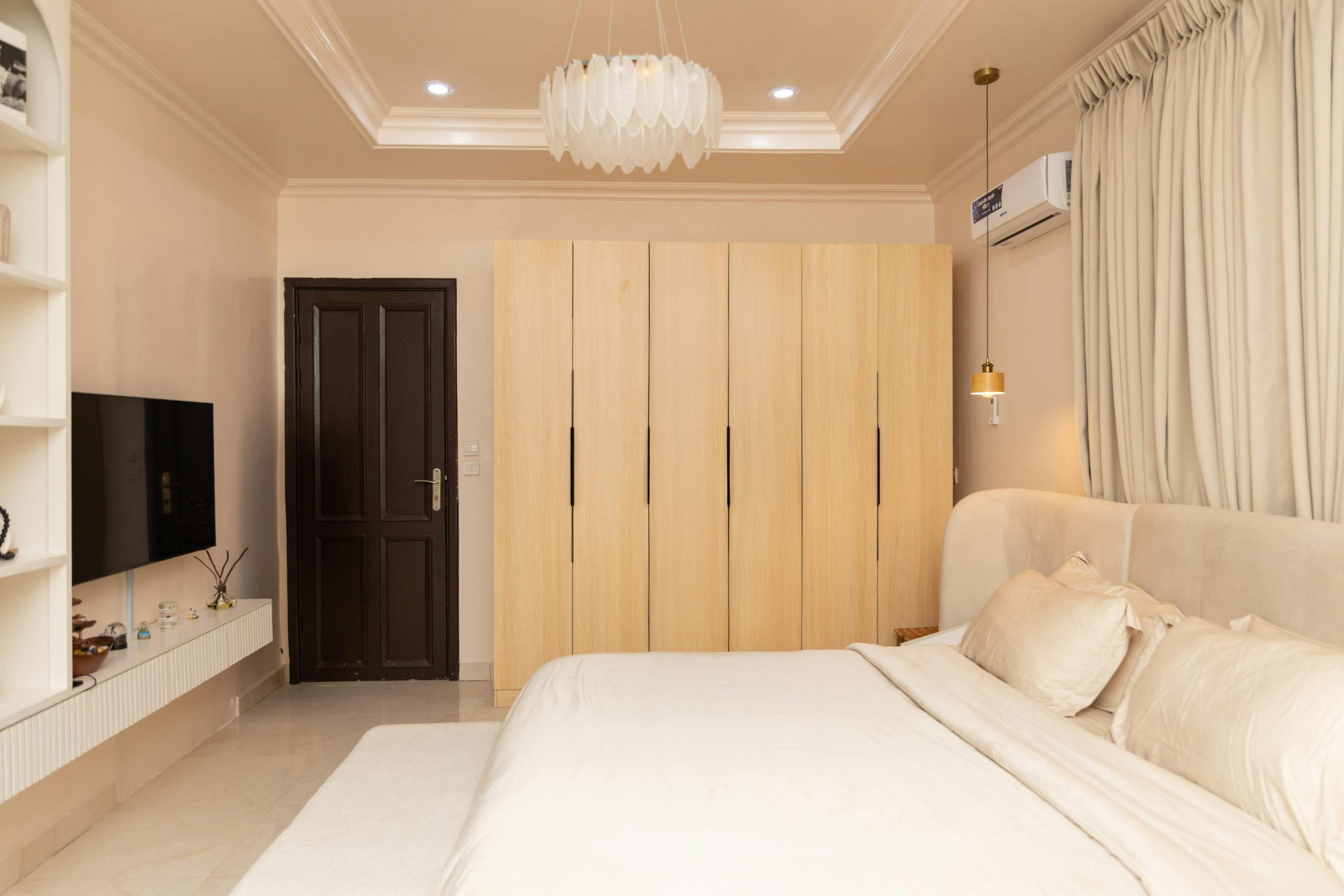 A serene and stylish modern bedroom with beige tones and minimalist furnishings.