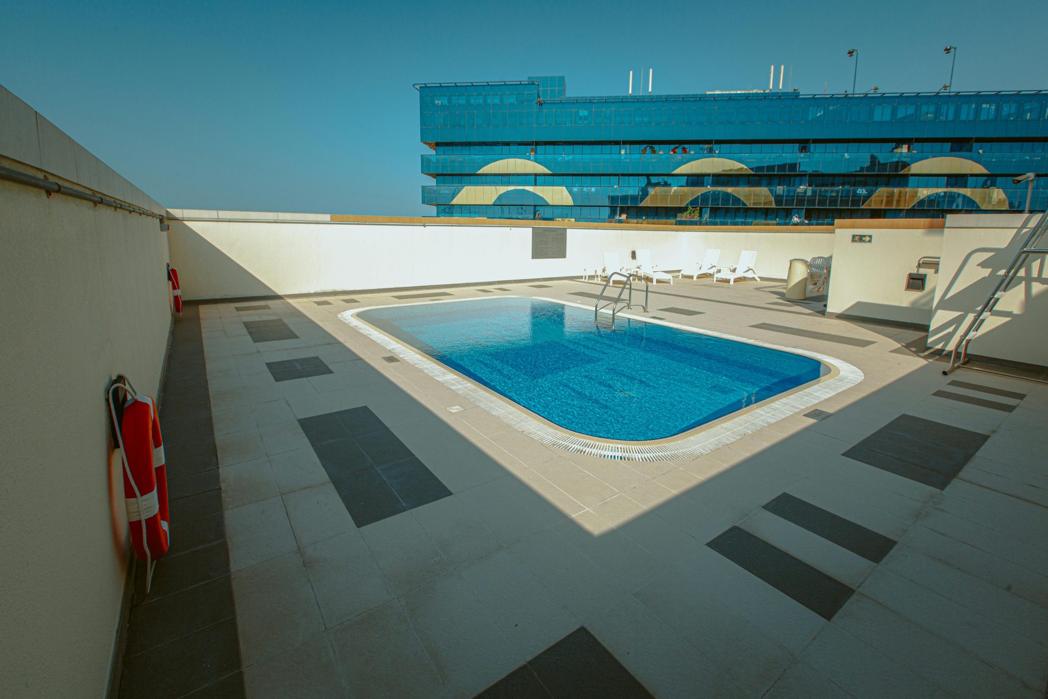 A serene rooftop pool with lounge chairs and modern architecture in the background.