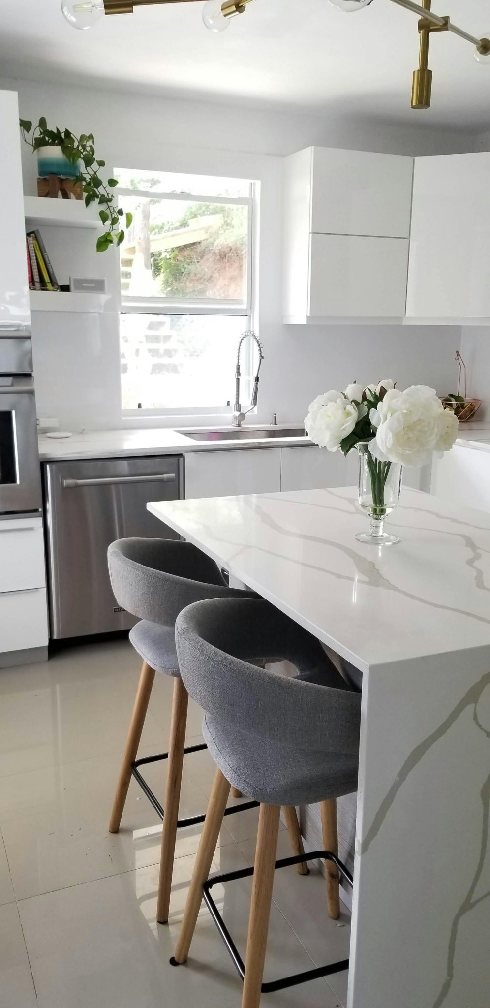 A sleek and modern kitchen featuring a white marble island and stylish decor.