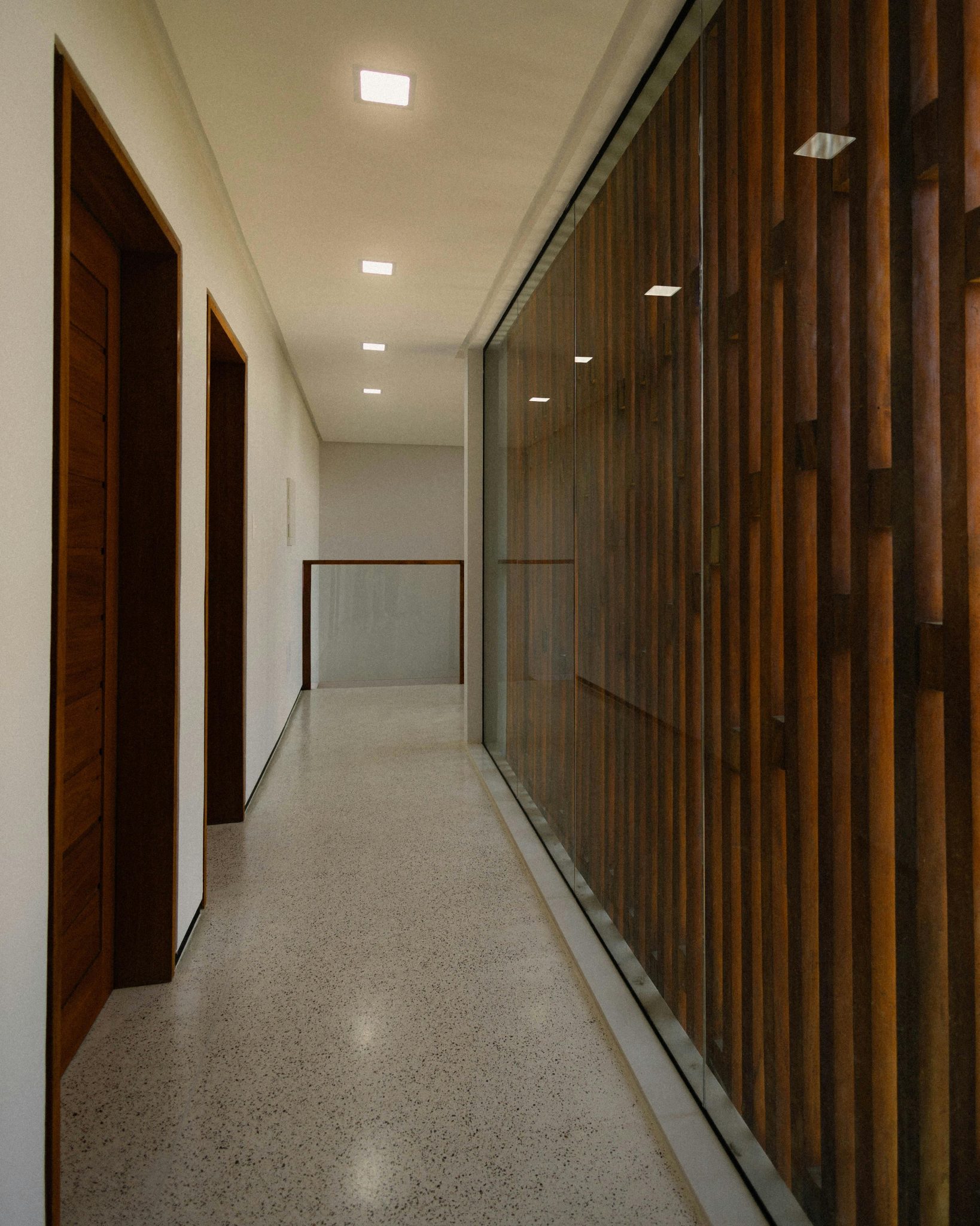 A sleek hallway featuring wood and glass panels under natural lighting.