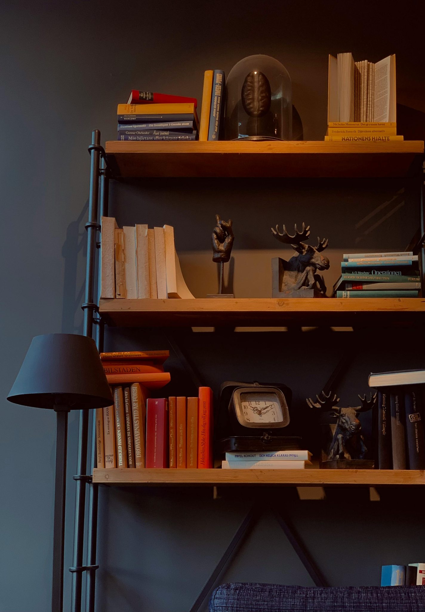 A stylish bookshelf adorned with books, figurines, and a lamp, creating a cozy interior space.