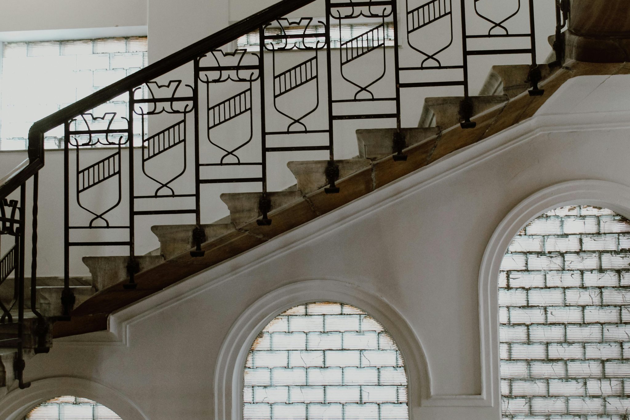 A stylish interior staircase featuring ornate metal railings and arched windows.