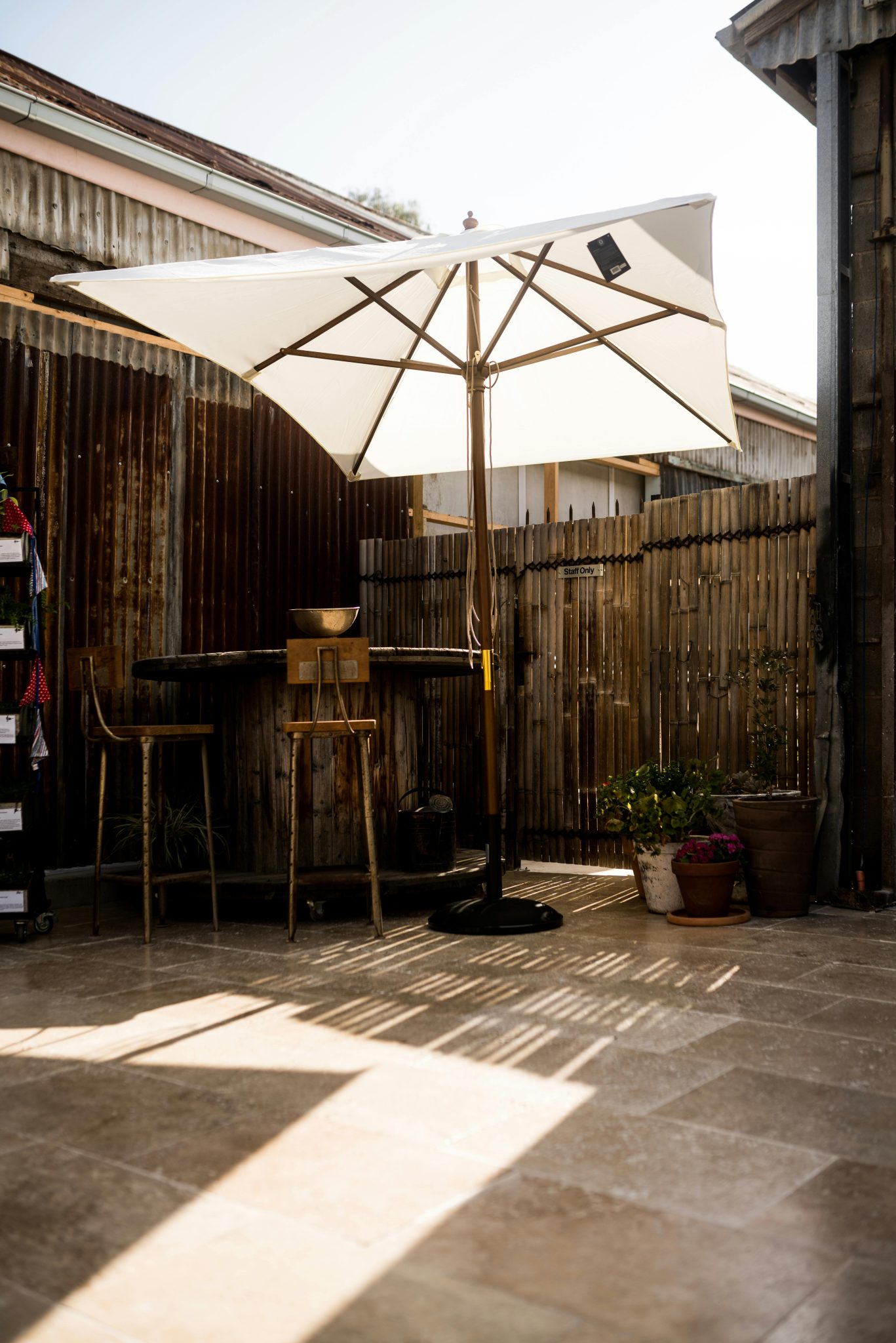 A sun-drenched terrace featuring a white umbrella and rustic decor, perfect for outdoor lounging.