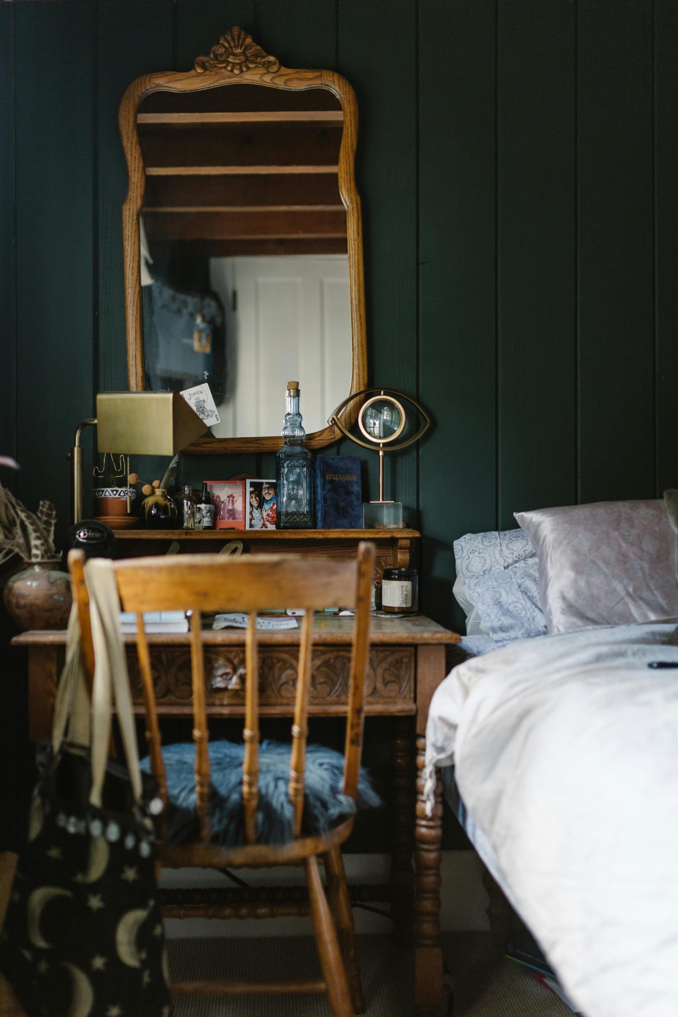 A vintage-style bedroom featuring ornate wooden furniture, mirror, and cozy decor elements.