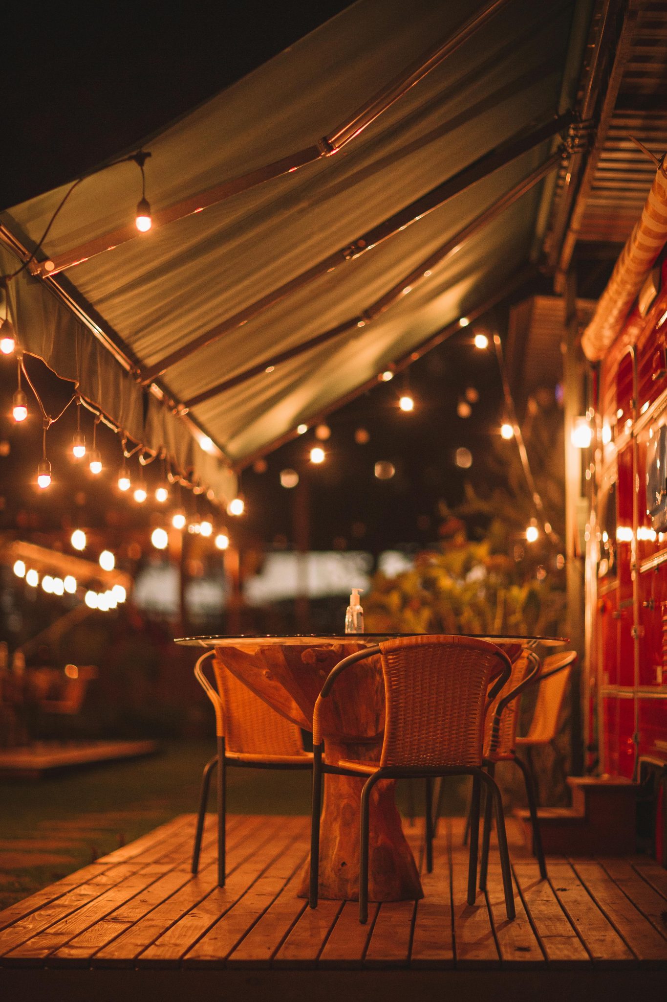 A warm outdoor restaurant setting with string lights and seating under a canopy at night.