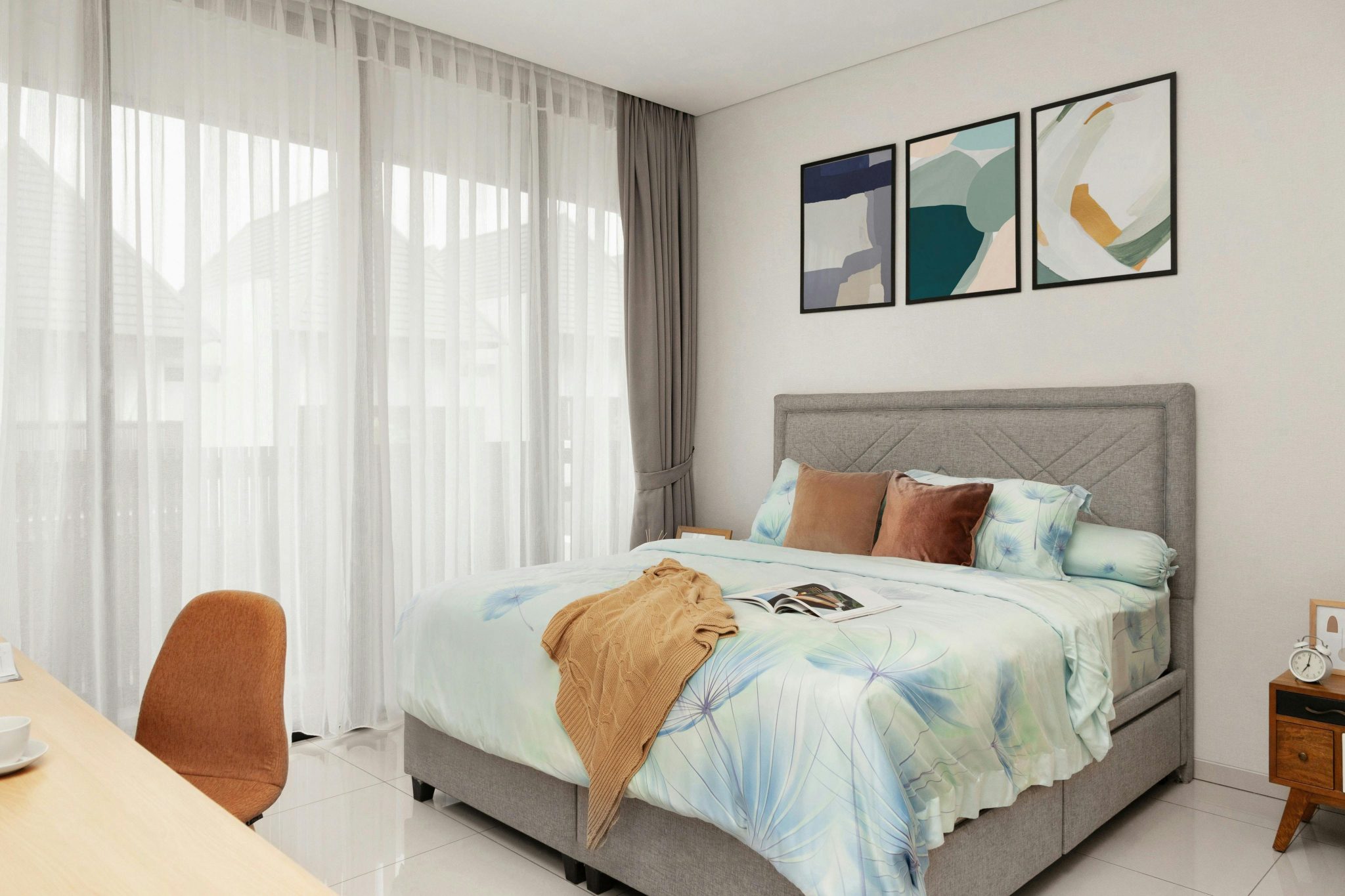 A well-decorated bedroom with modern art and a cozy bed setup in natural light.