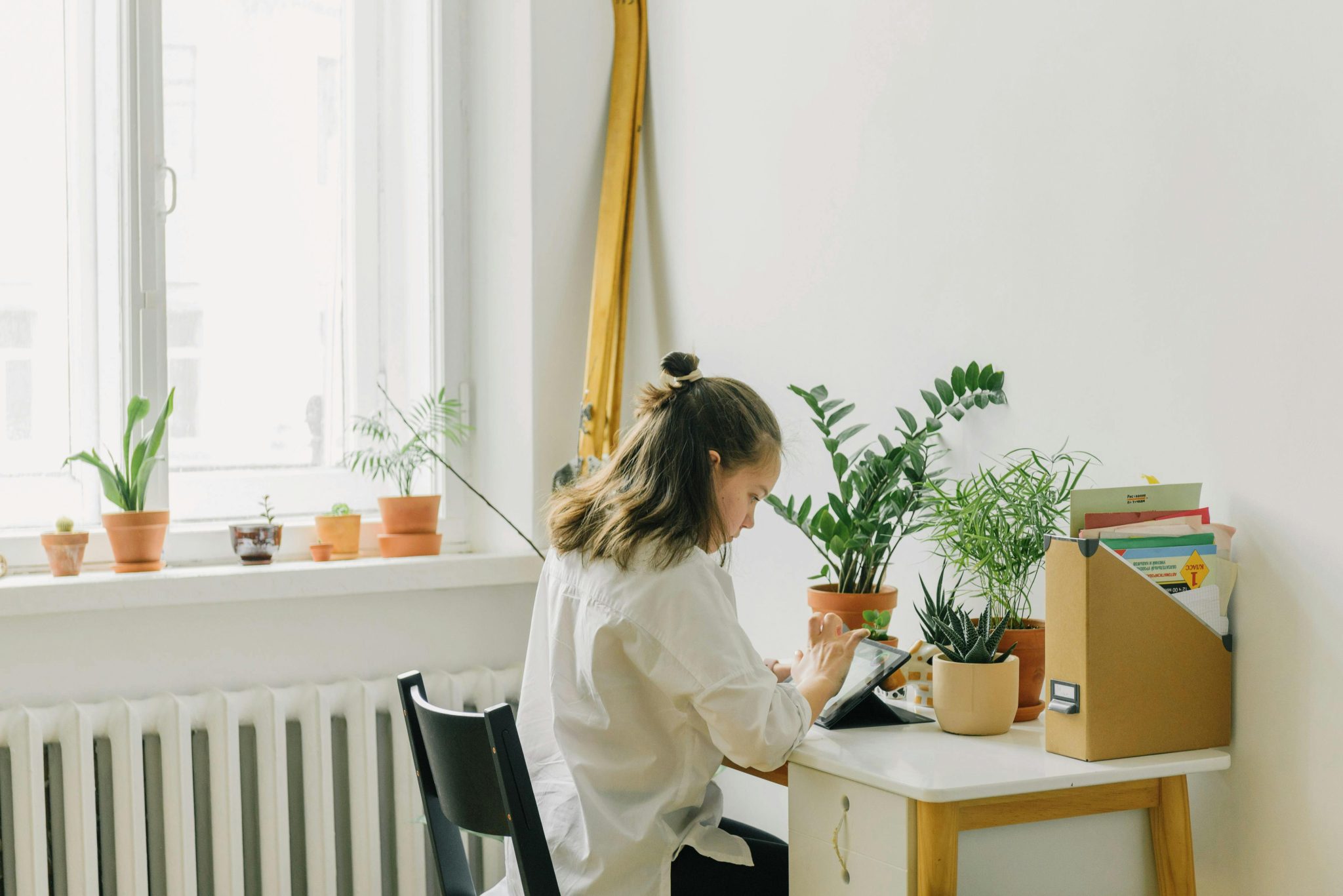 A woman sits at a desk surrounded by potted plants, creating a serene working environment.