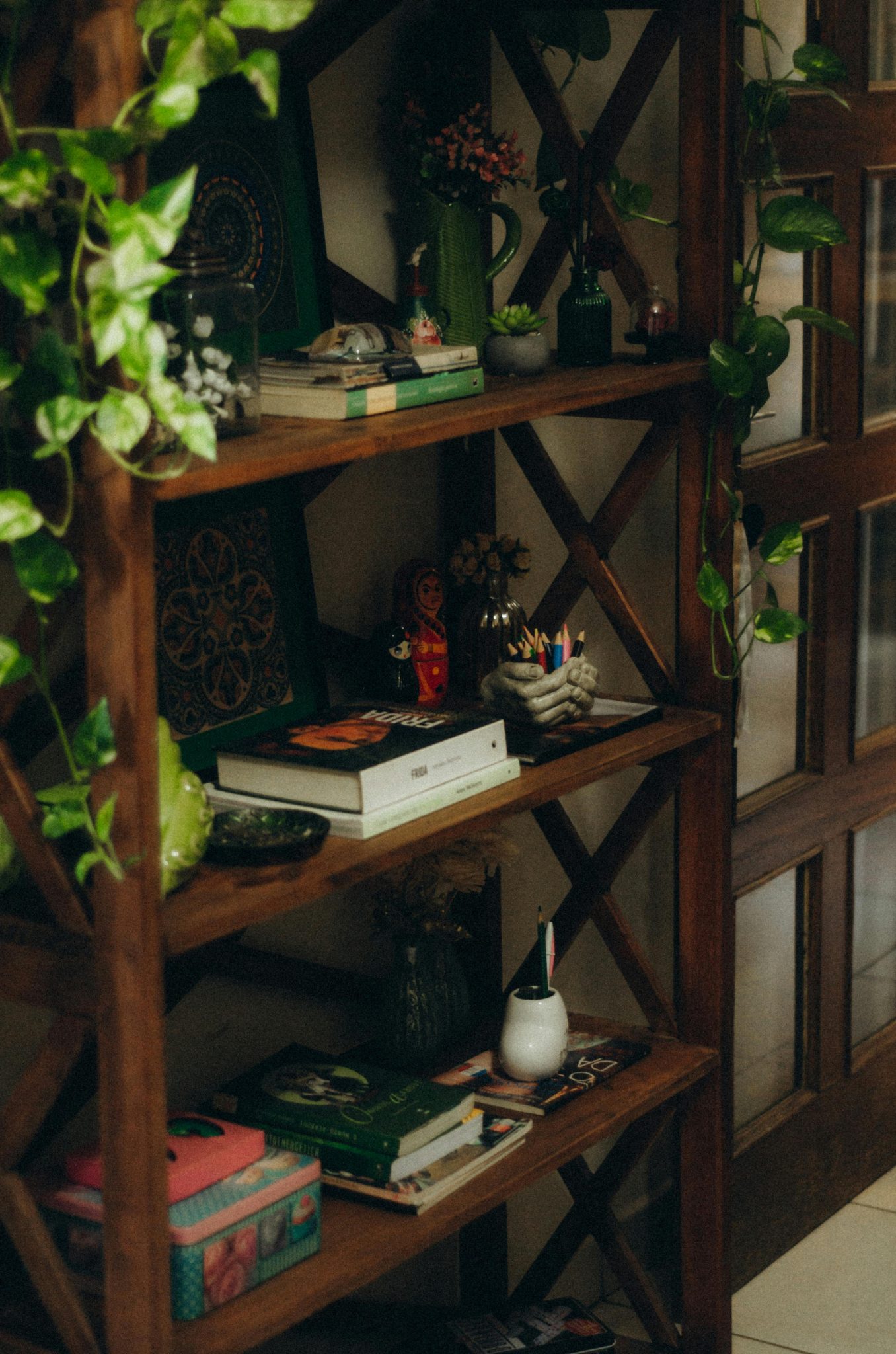 A wooden bookshelf adorned with books, decorations, and houseplants, creating a cozy indoor atmosphere.