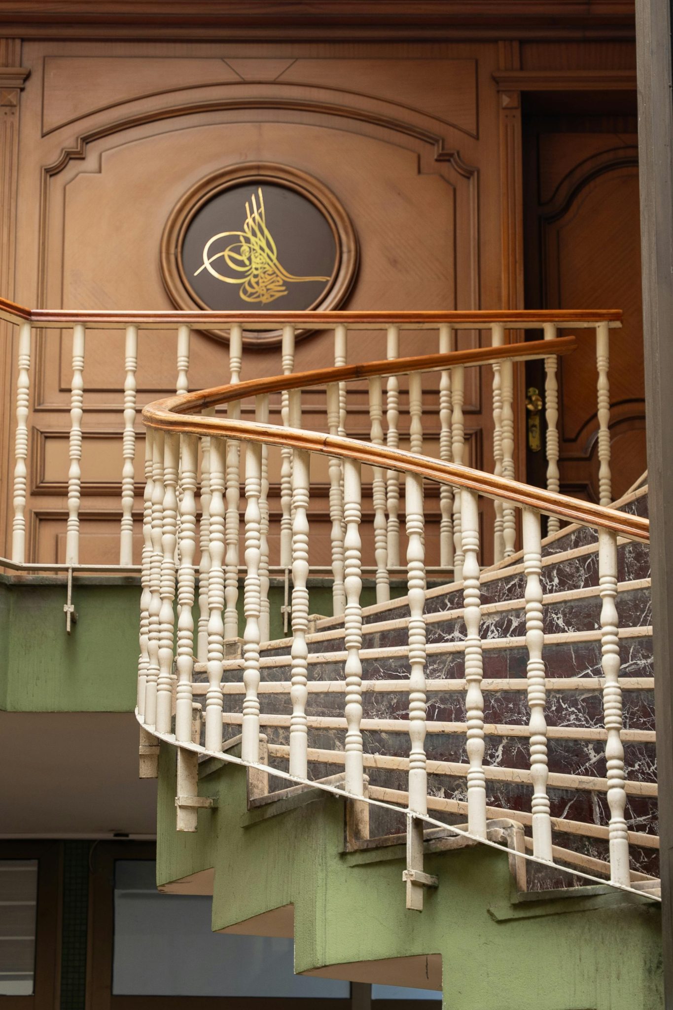 Aesthetic curved staircase with ornate white railings and wooden accents in a classical architectural setting.
