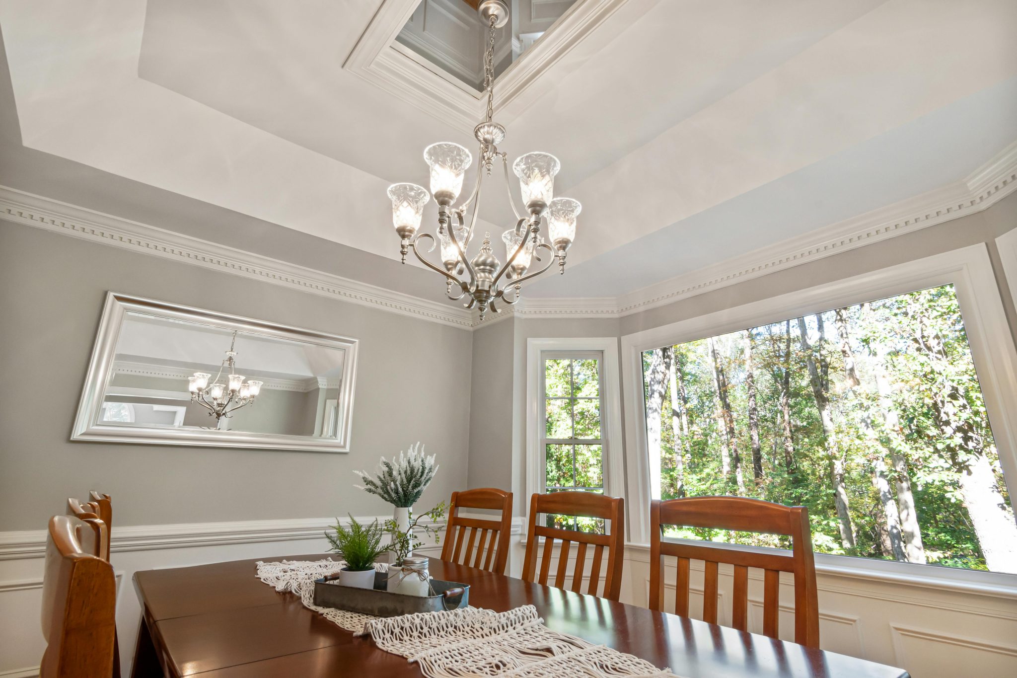 Beautiful dining room featuring a classic chandelier, wooden furniture, and ample natural light from large windows.