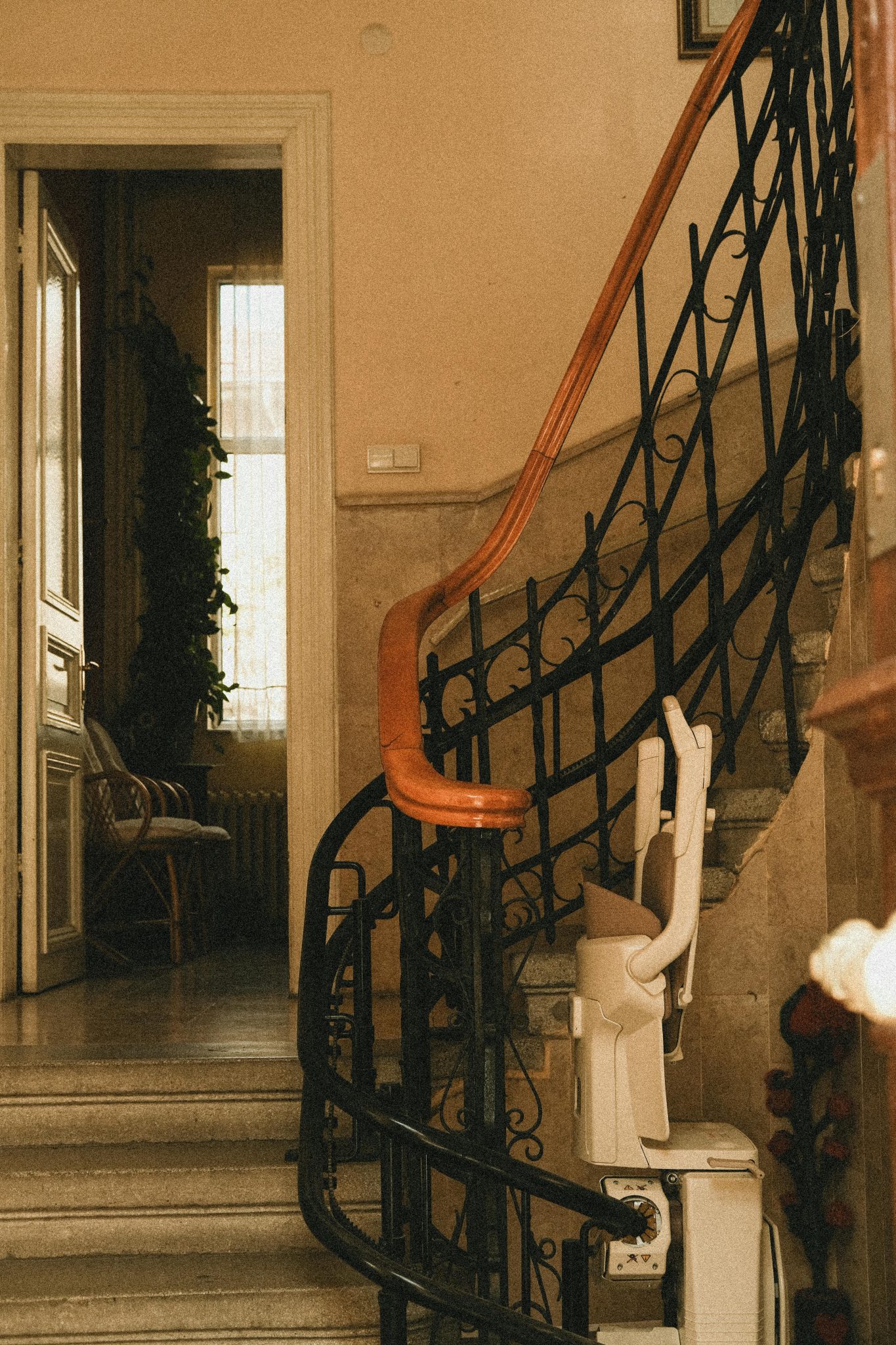 Beautiful interior staircase with wrought iron railings and stair lift, featuring a warm, inviting atmosphere.