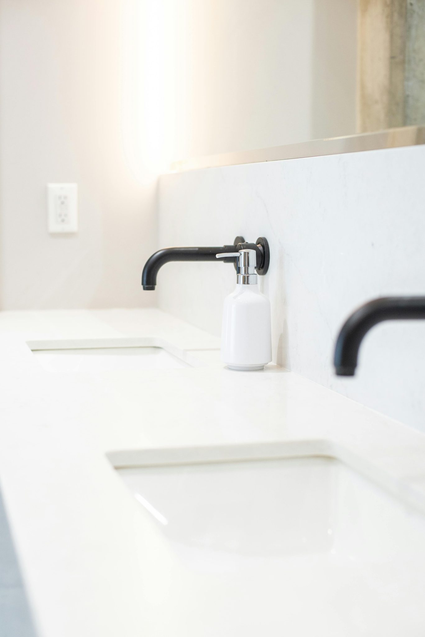 Bright and clean bathroom featuring dual sinks and a modern soap dispenser.