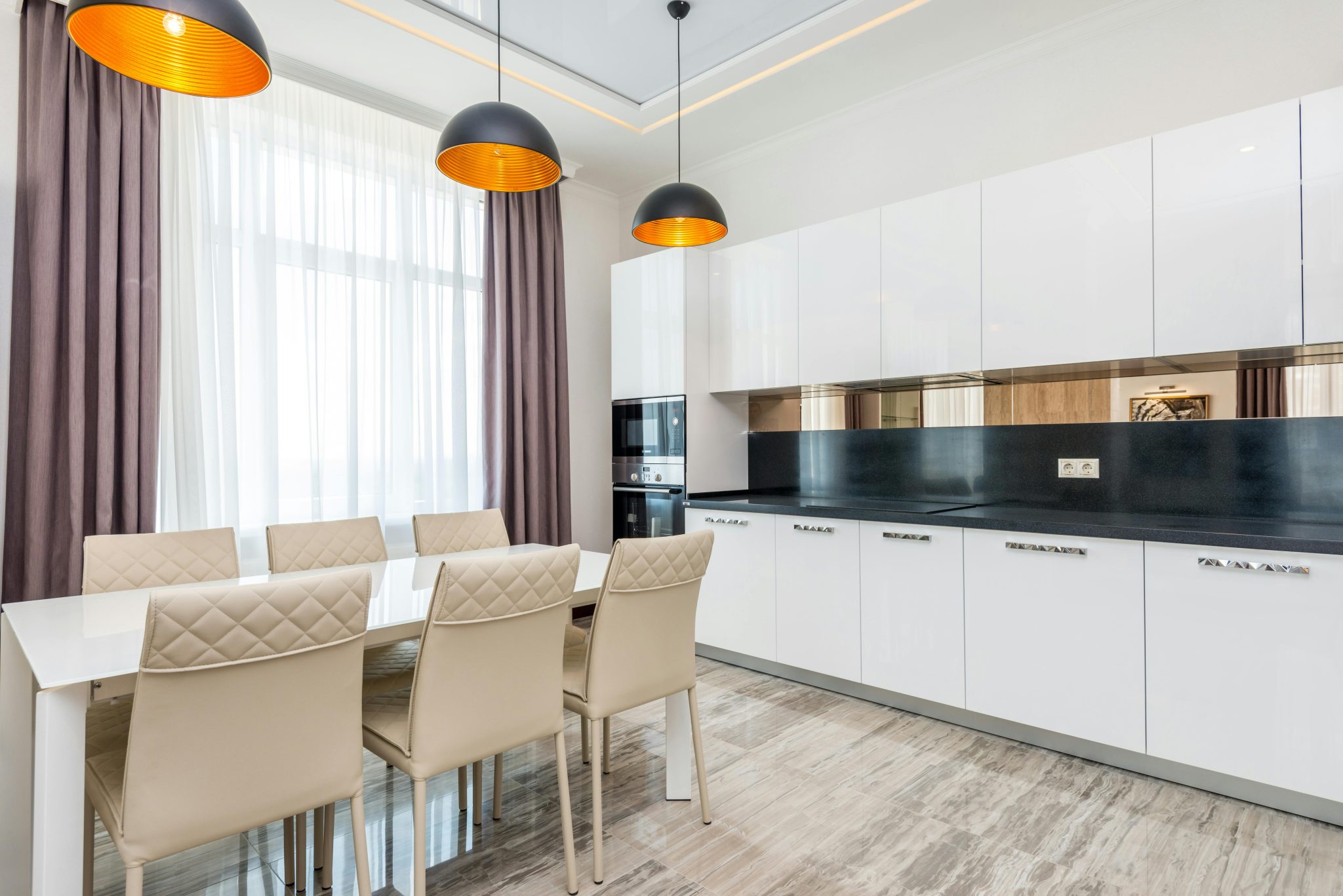 Bright contemporary kitchen with sleek white cabinetry and stylish dining setup.