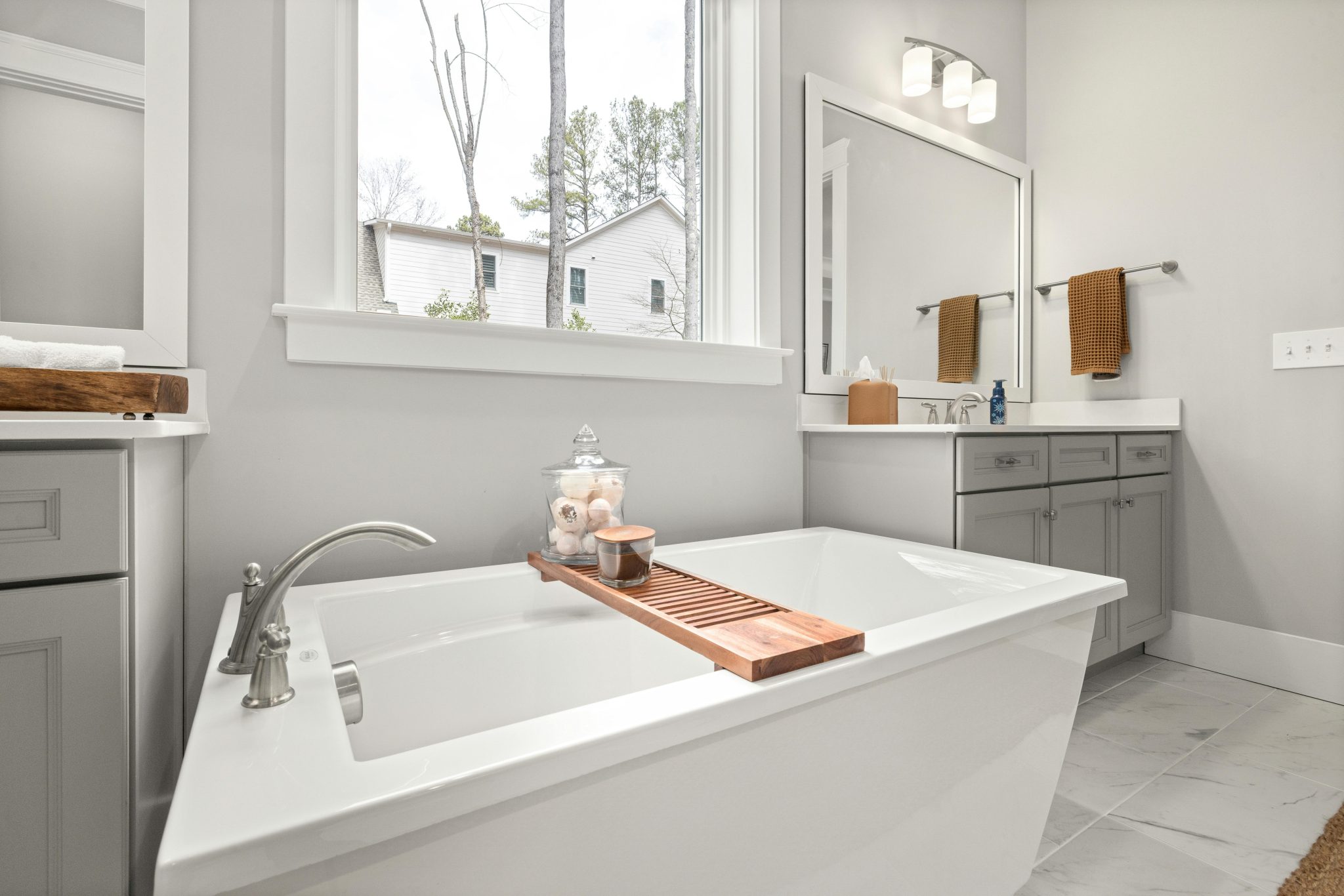 Bright modern bathroom featuring a luxurious soaking tub and large window overlooking an outdoor view.