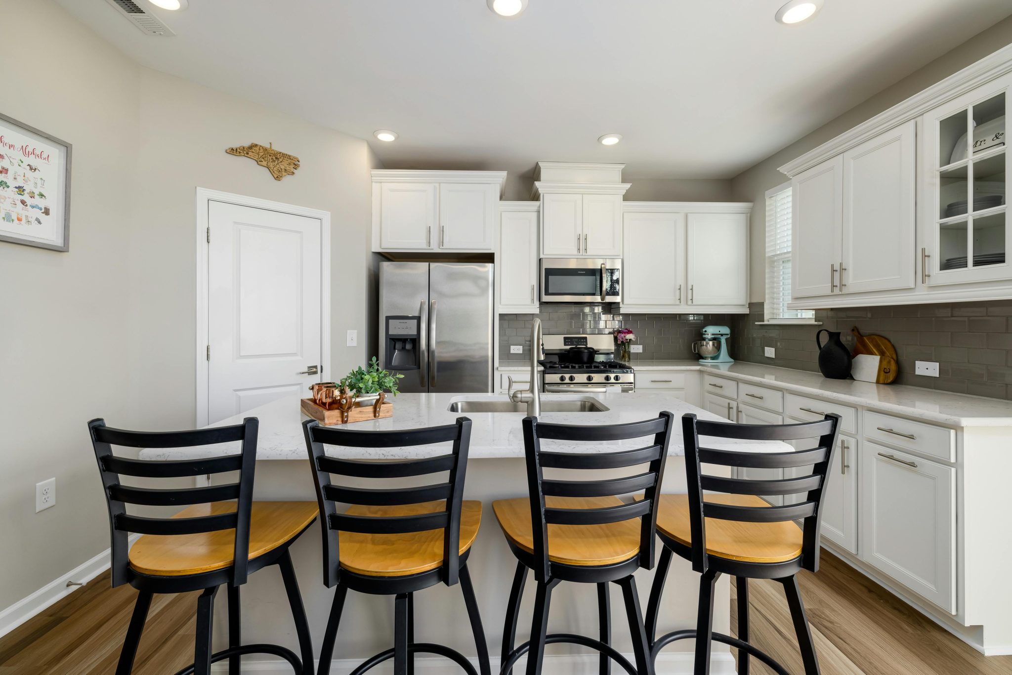 Bright modern kitchen interior featuring sleek design, bar seating, and stainless steel appliances.