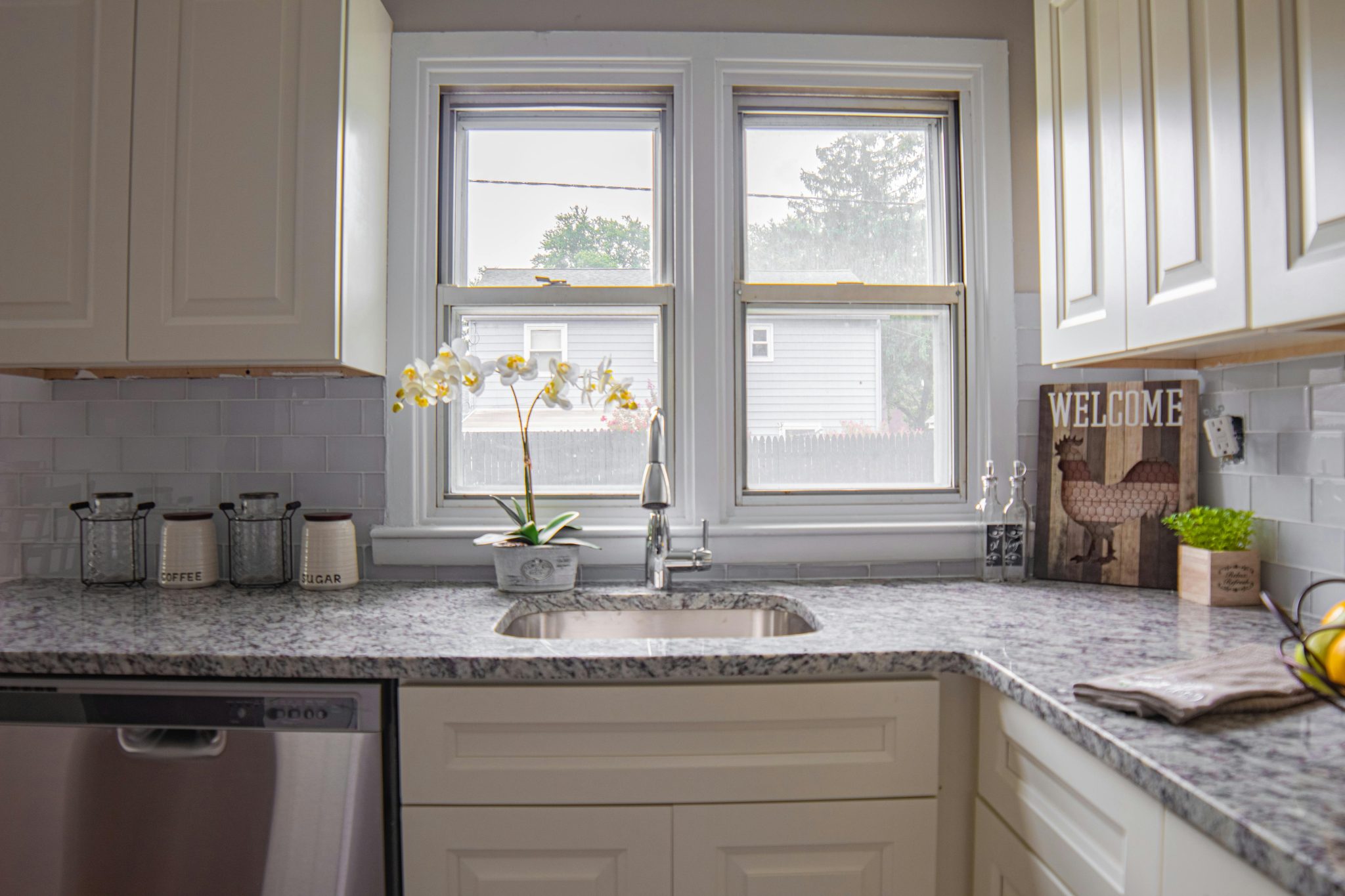 Bright modern kitchen with large windows, granite countertops, and decorative elements.
