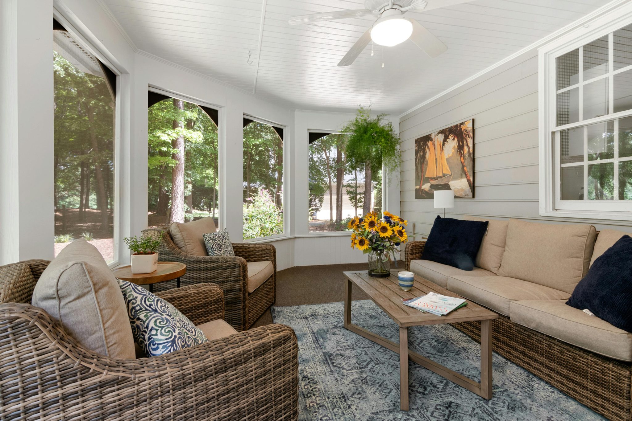Bright sunroom featuring wicker furniture, cozy seating, and lush greenery for a relaxing atmosphere.