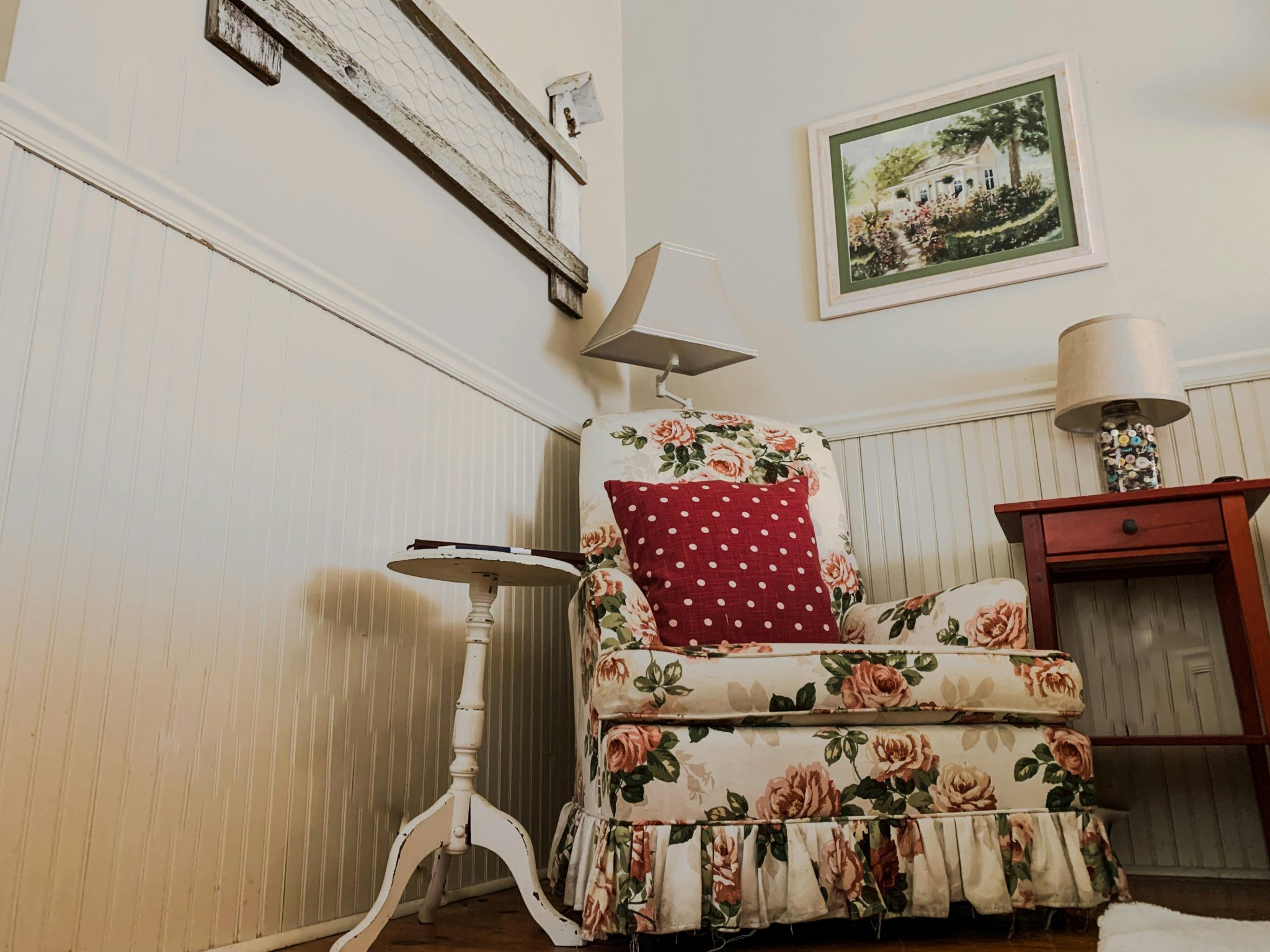 Charming floral armchair with red polka dot pillow in a cozy vintage living room, perfect for interior design inspiration.