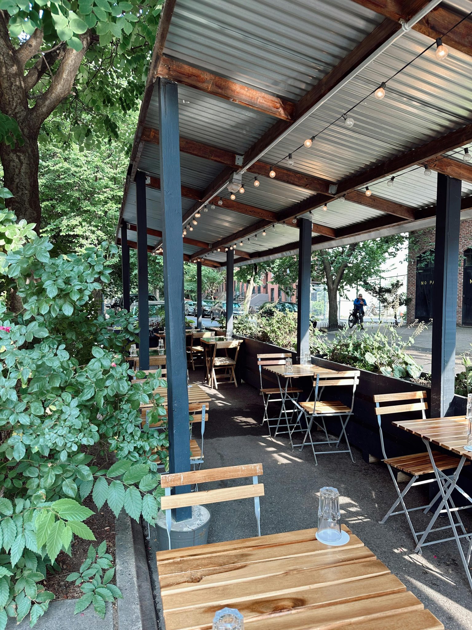Charming outdoor cafe in New York City with wooden tables and chairs under a canopy.