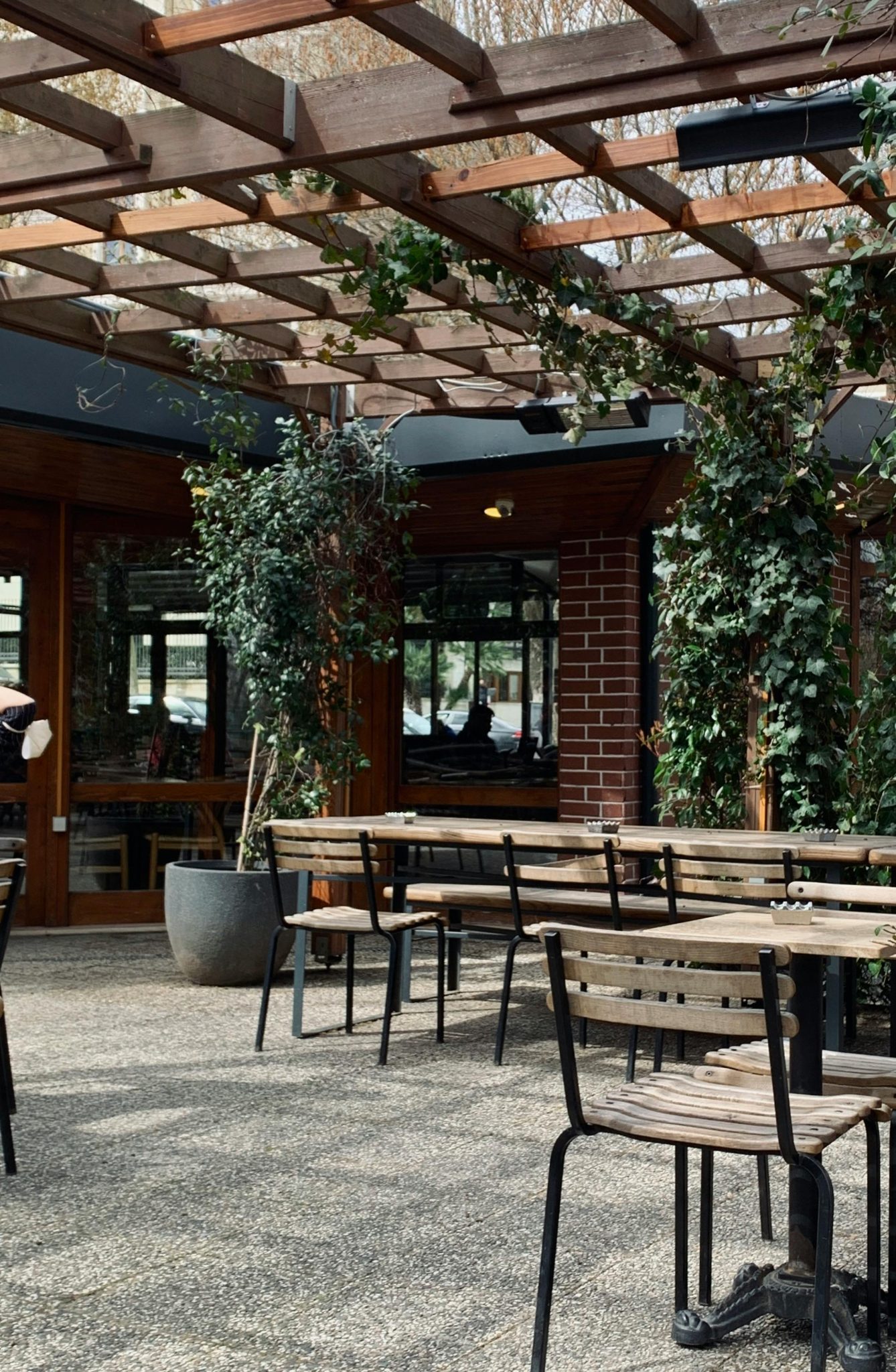 Charming outdoor patio with wooden furniture, lush plants, and natural light filtering through a trellis.