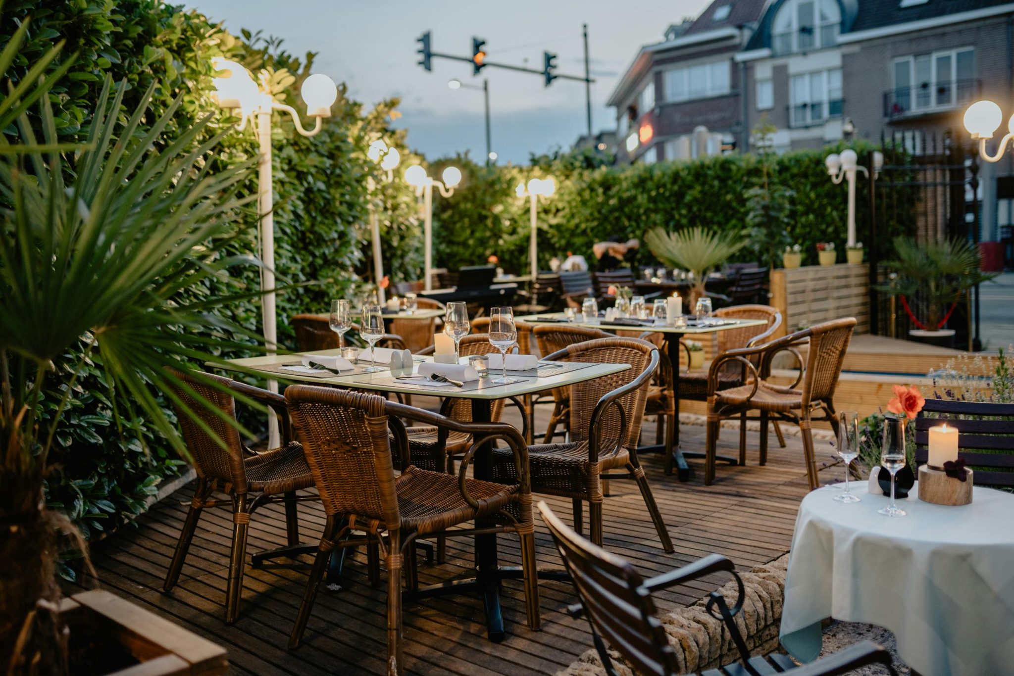 Charming restaurant terrace with wicker chairs and glowing lights, perfect for a relaxed evening.