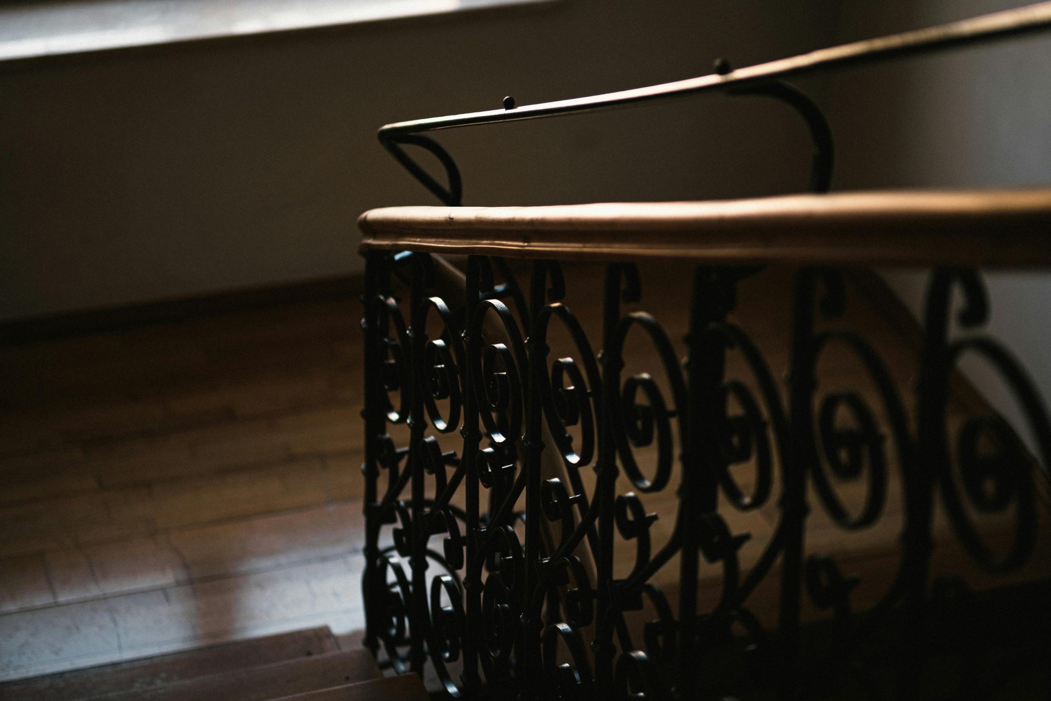 Close-up of a beautifully designed spiral staircase featuring ornate metal railing and wooden steps.
