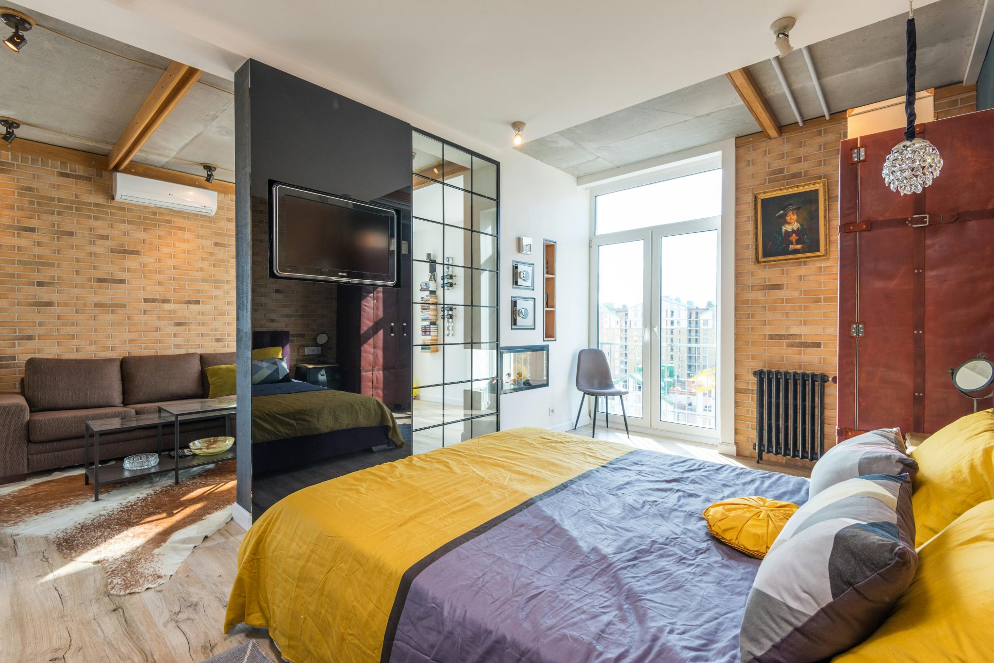 Comfortable bed with pillows and soft blanket in cozy bedroom zone in modern apartment