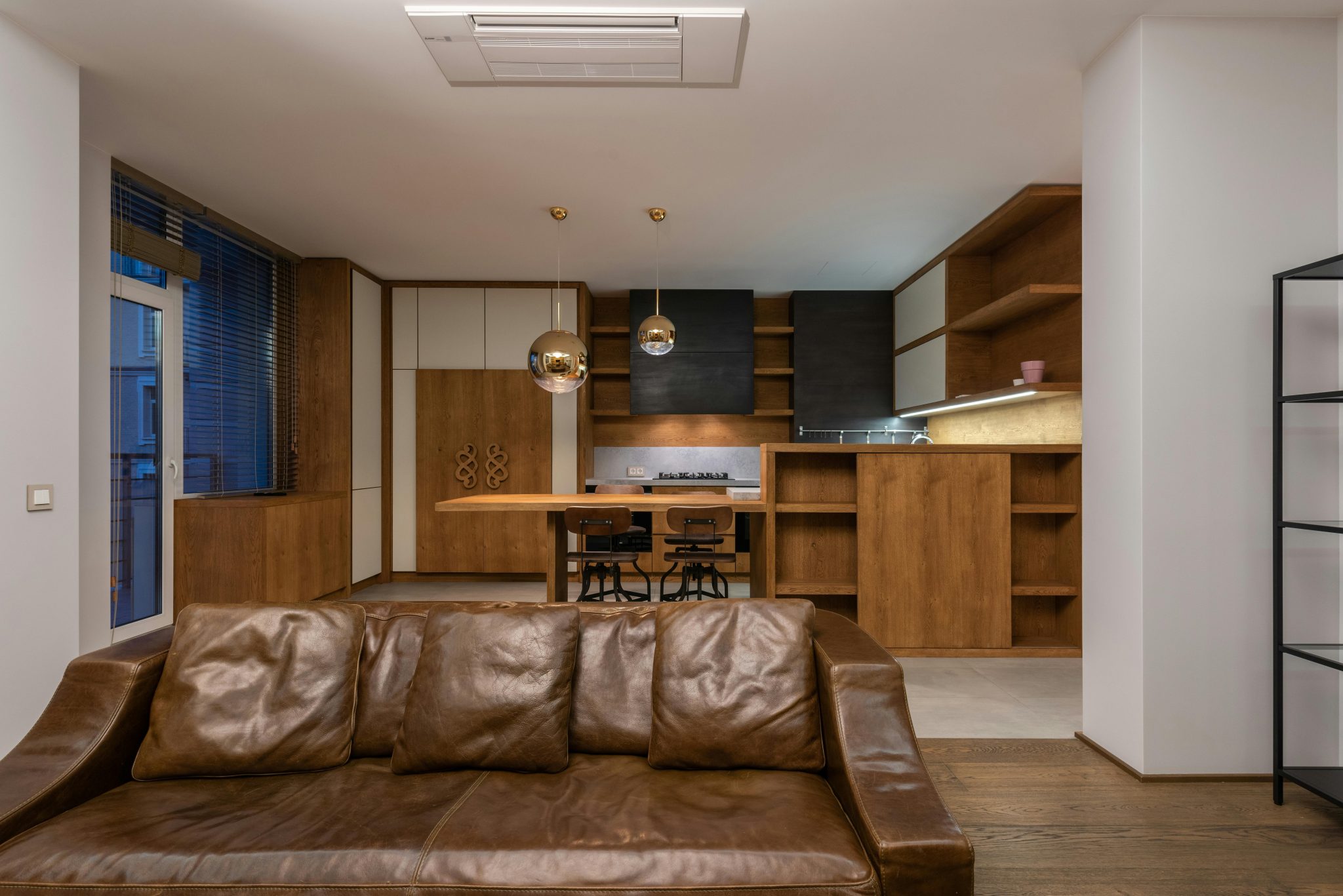 Comfortable leather sofa with pillows in contemporary apartment with modern interior and shelves