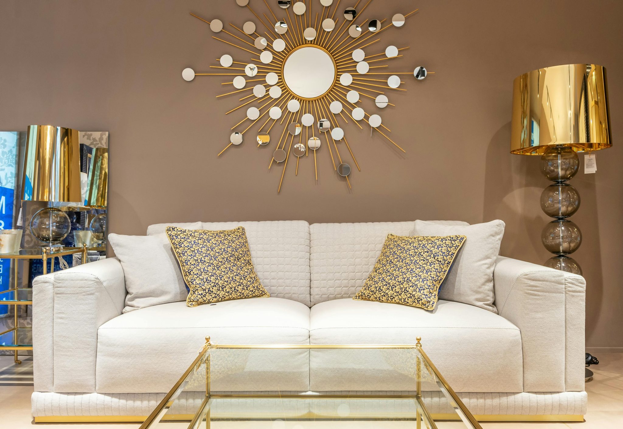 Comfortable white sofa with pillows placed near with floor lamp at wall with decorative elements in stylish living room of apartment
