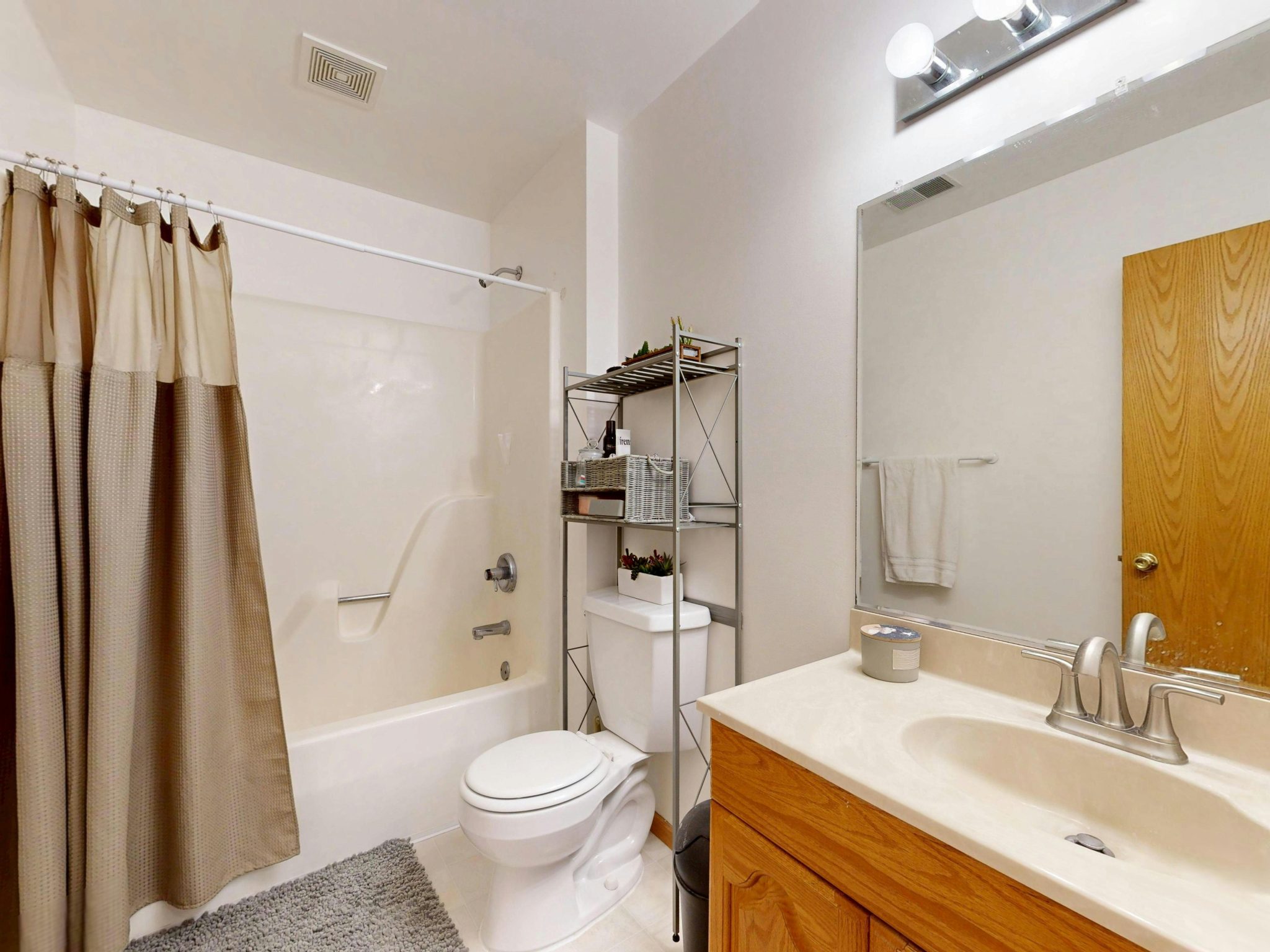 Contemporary bathroom featuring a beige shower curtain, sink, and toilet.