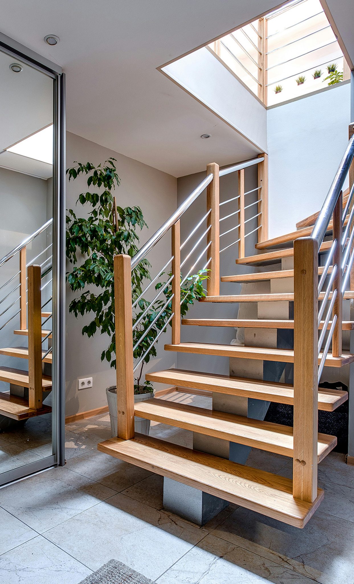 Contemporary interior design featuring a stylish wooden staircase under a skylight.